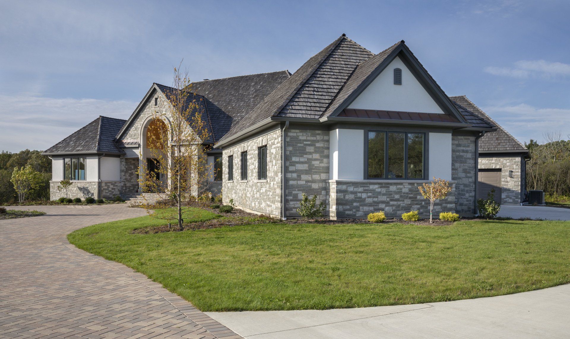 A large house with a lot of windows is sitting on top of a lush green lawn.