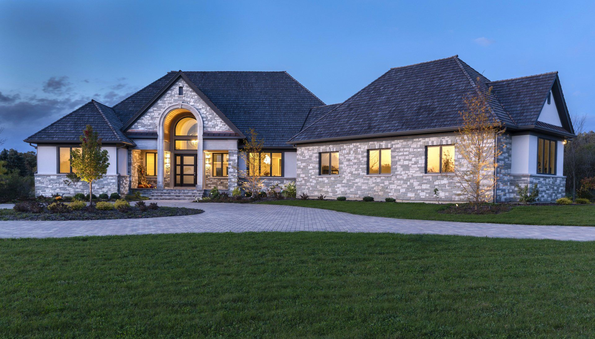 A large house with a lot of windows is sitting on top of a lush green field.