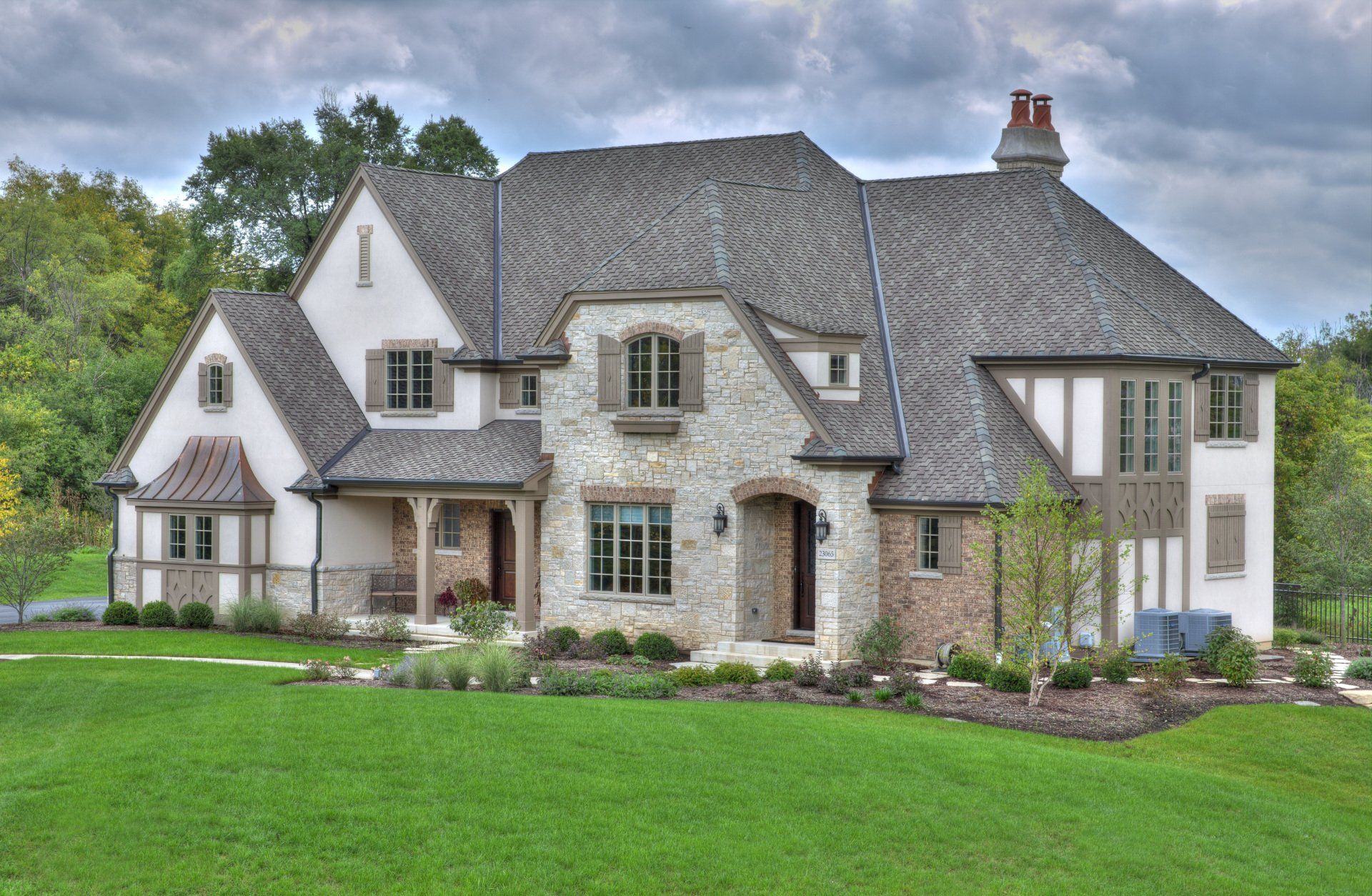 A large house with a gray roof is sitting on top of a lush green field.