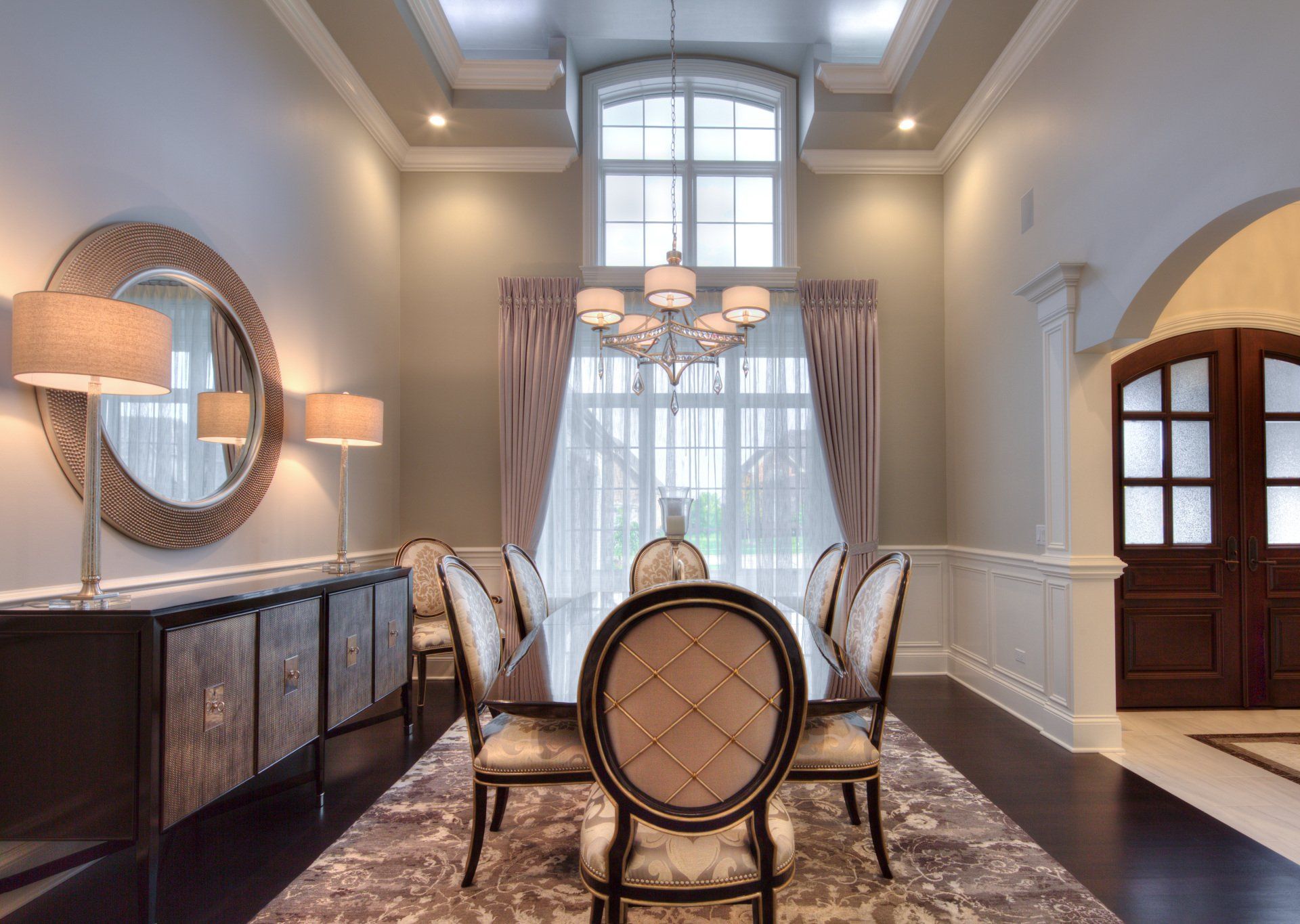 A dining room with a table and chairs and a mirror on the wall.