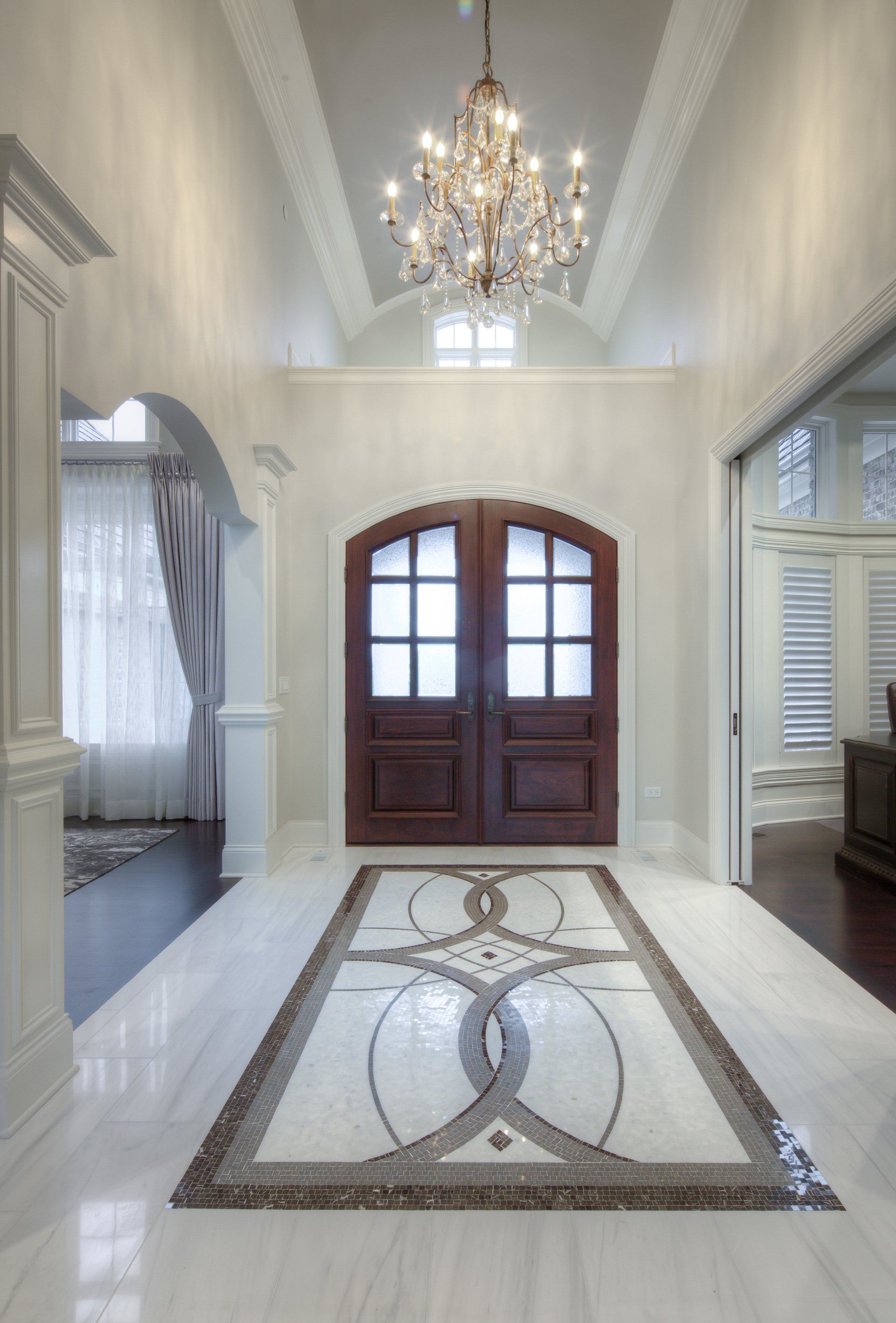 There is a chandelier hanging from the ceiling in the hallway.