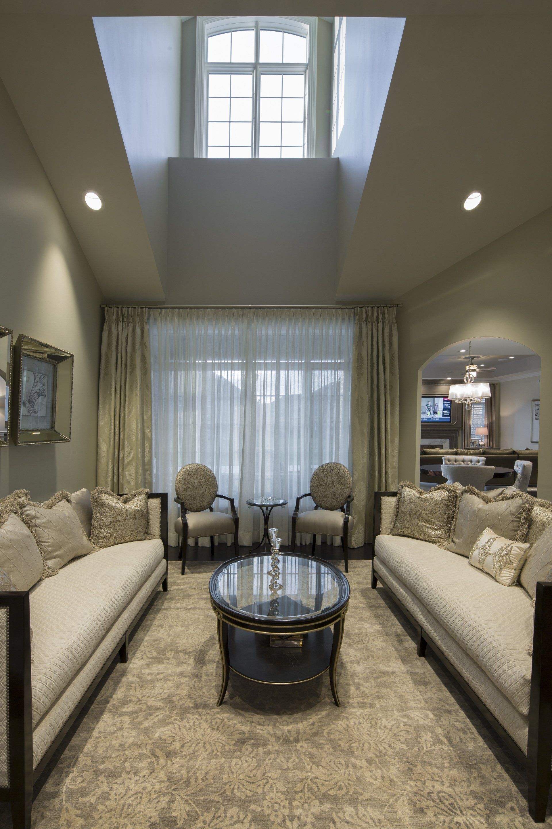 A living room with two couches , two chairs , a coffee table and a skylight.
