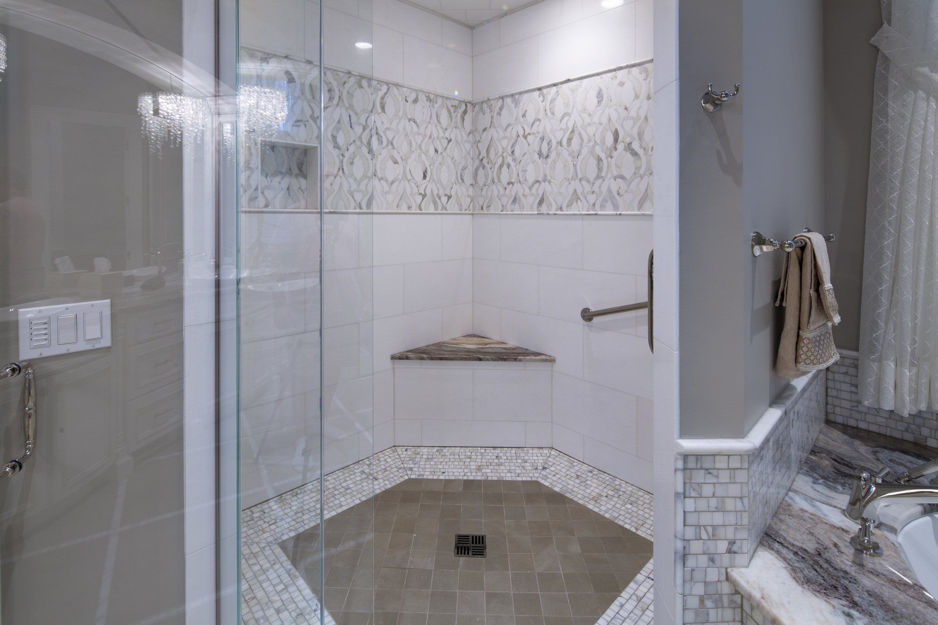 A bathroom with a walk in shower with a glass door and a bench.