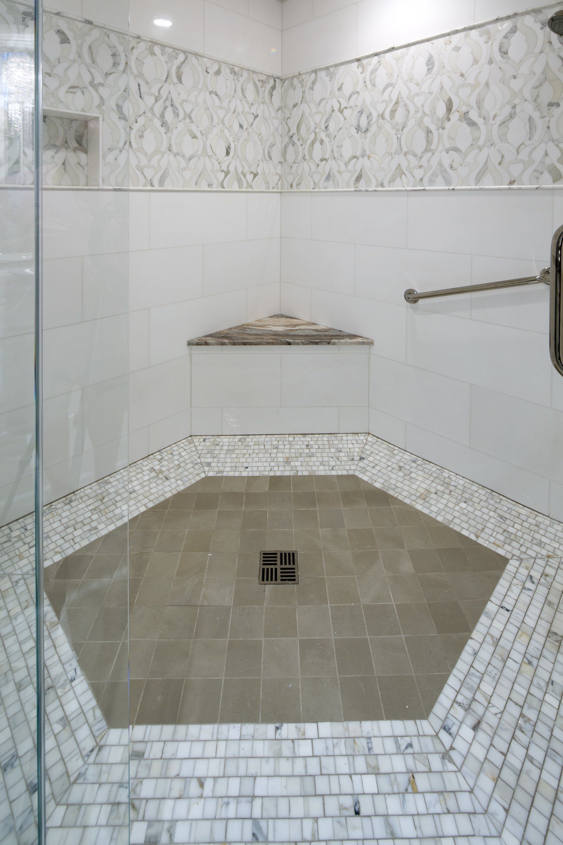 A walk in shower with a tiled floor and a glass door.