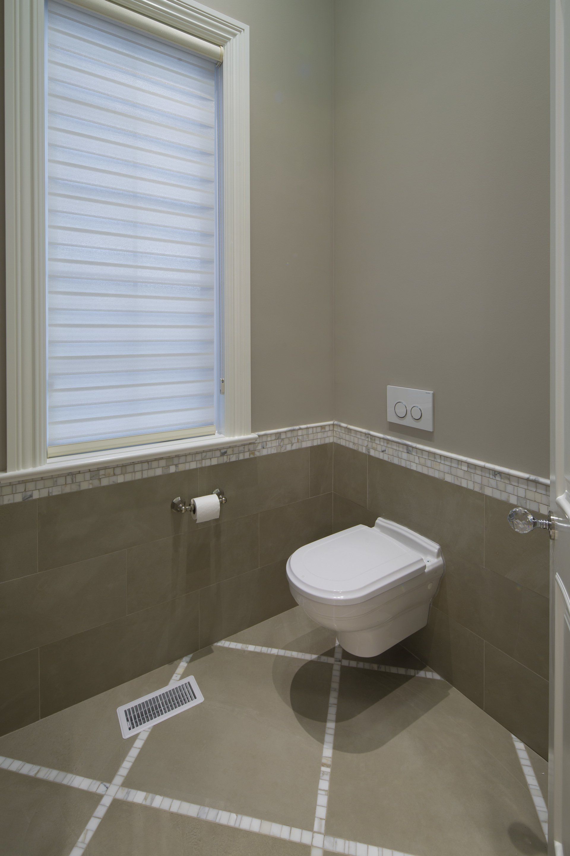 A bathroom with a toilet and a window.