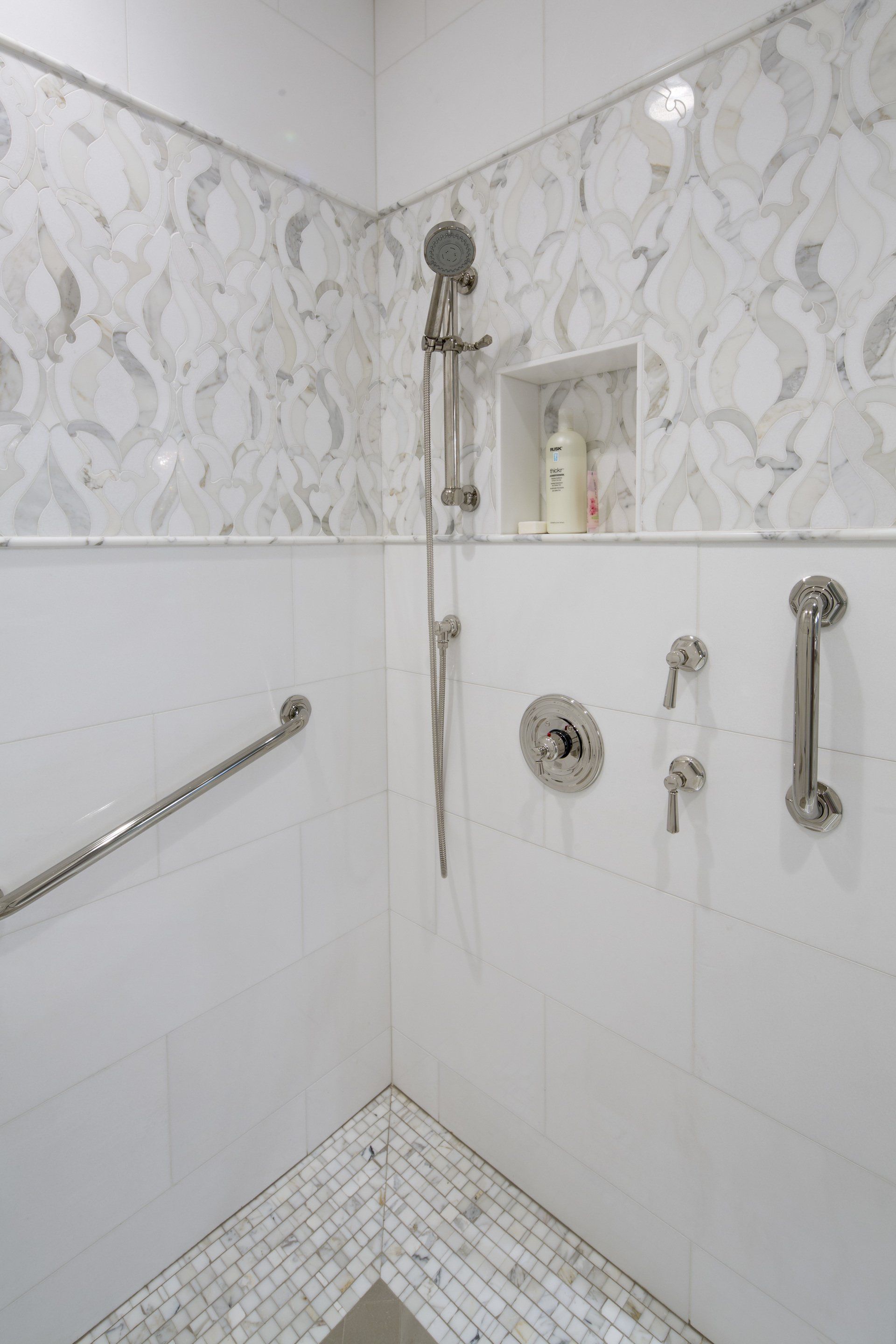 A bathroom with a walk in shower with a hand rail.