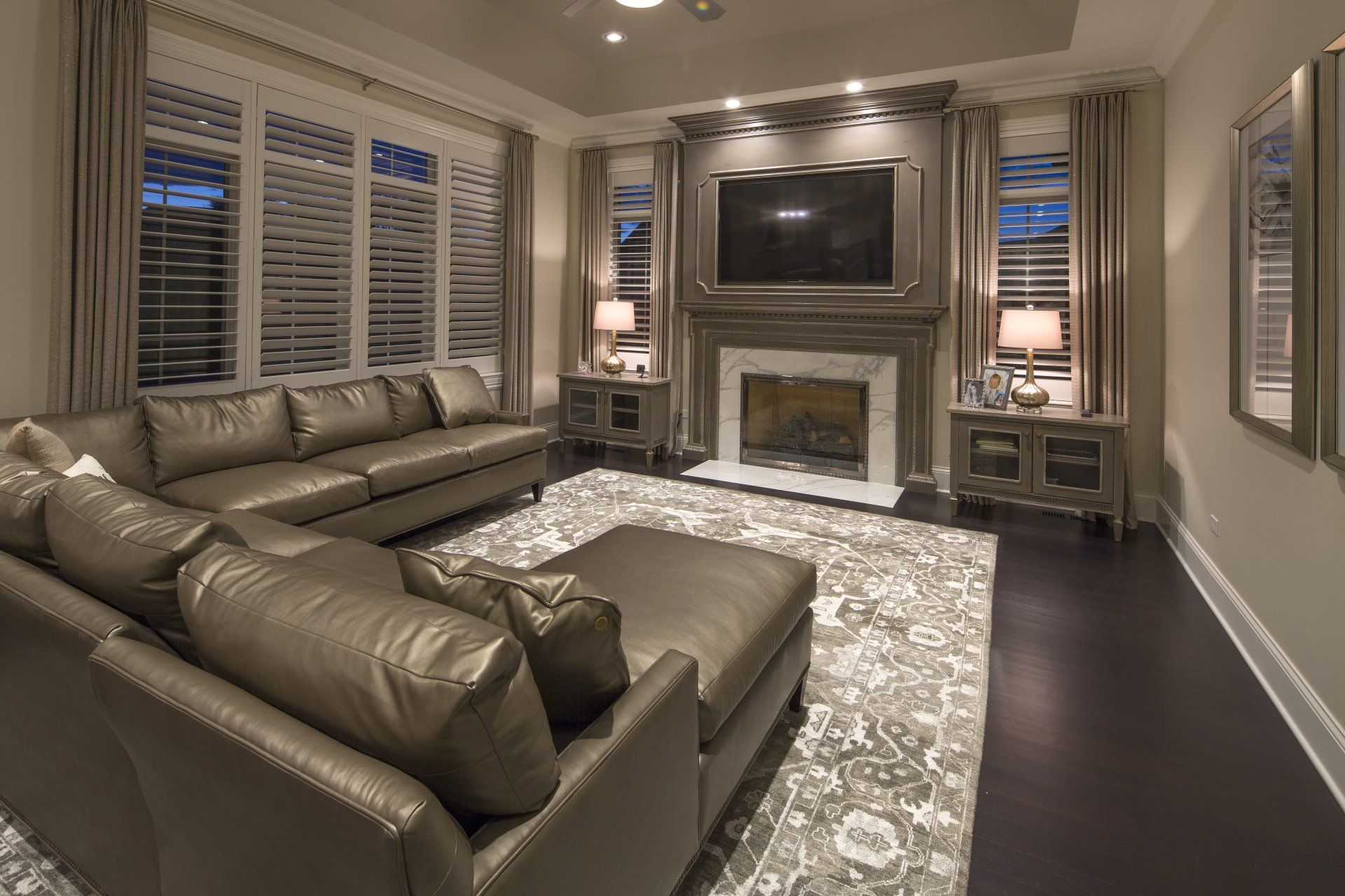 A living room with a couch , ottoman , fireplace and television.