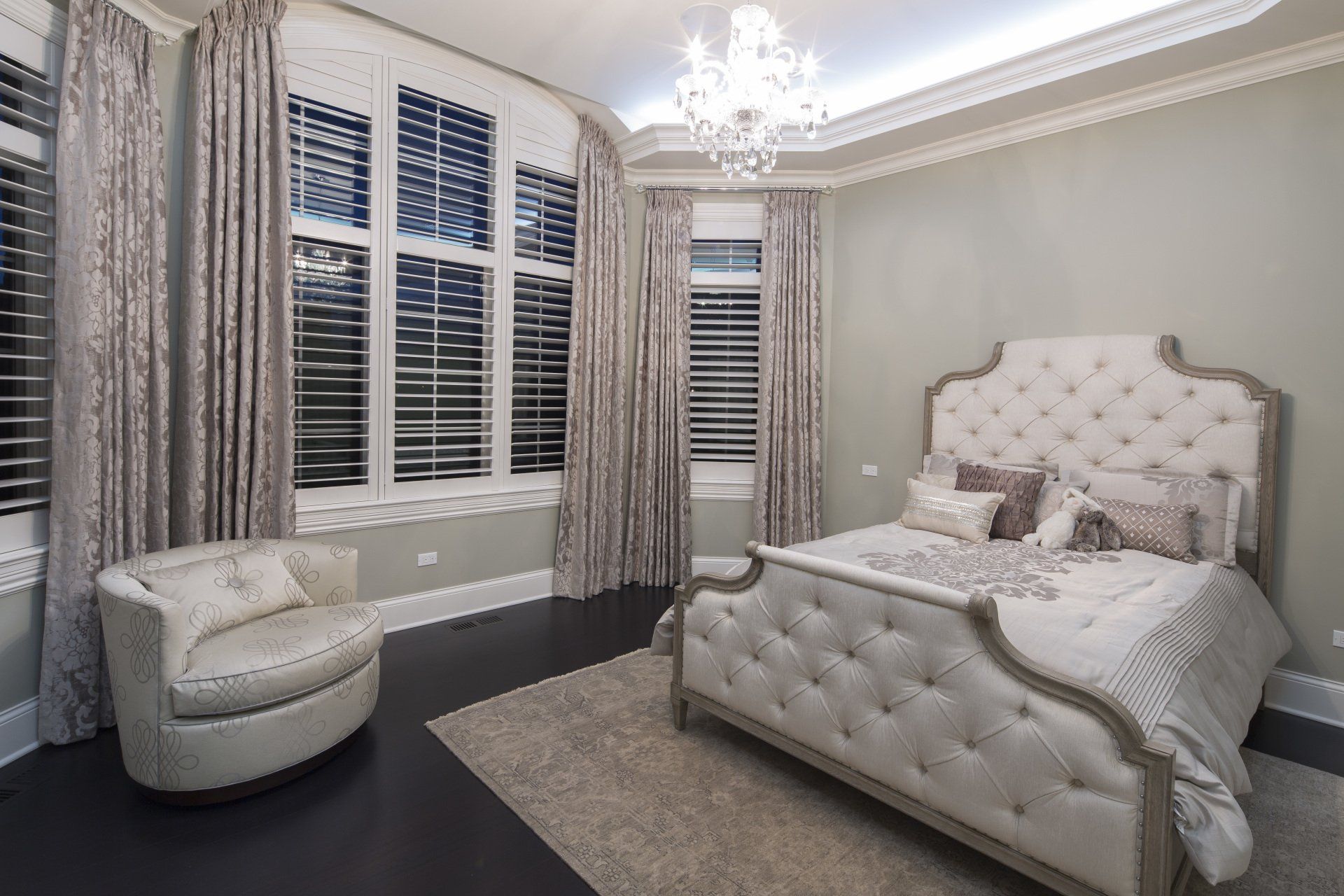 A bedroom with a bed , chair , and chandelier.