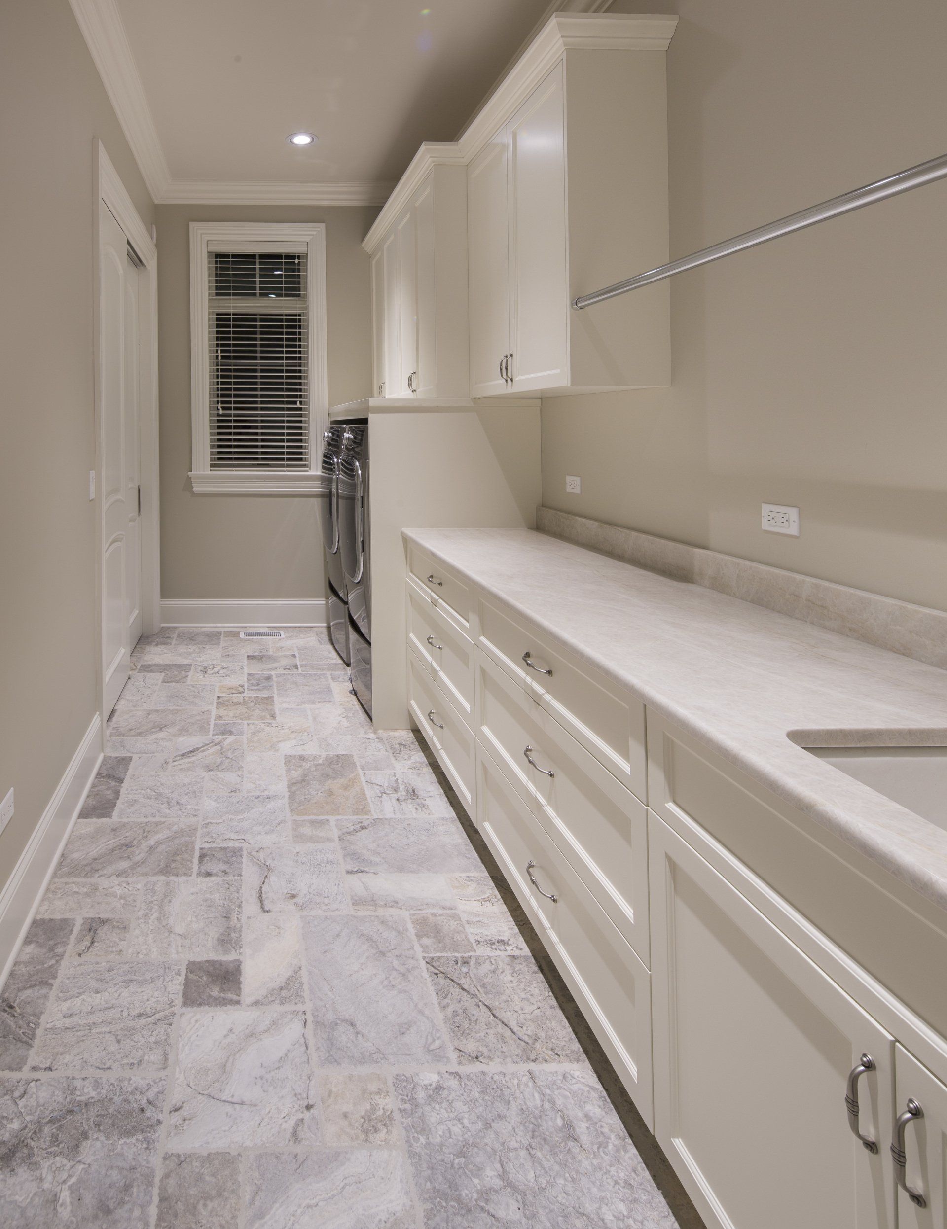 A laundry room with white cabinets , a sink , and a washer and dryer.