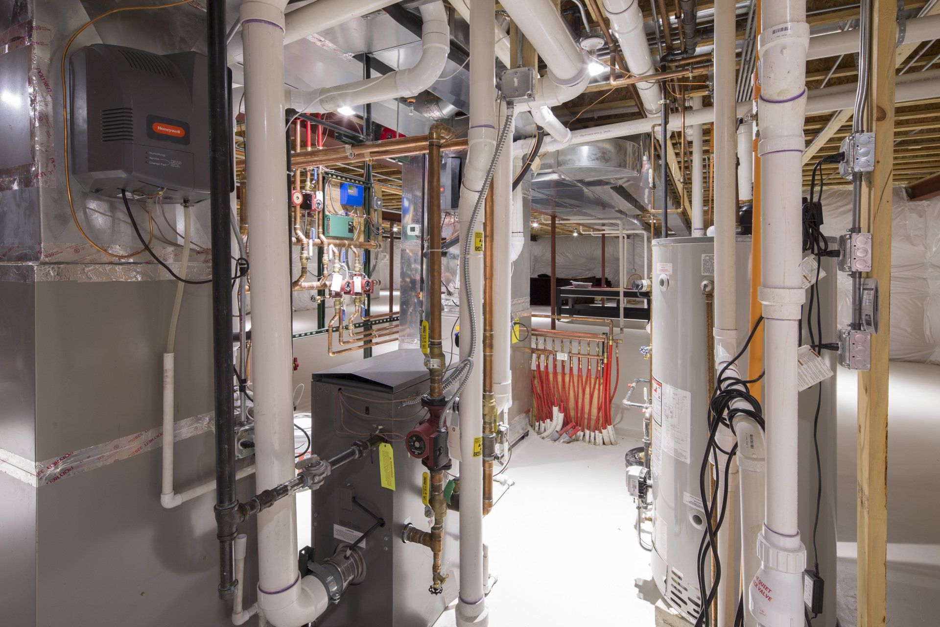 A basement with a lot of pipes and appliances.