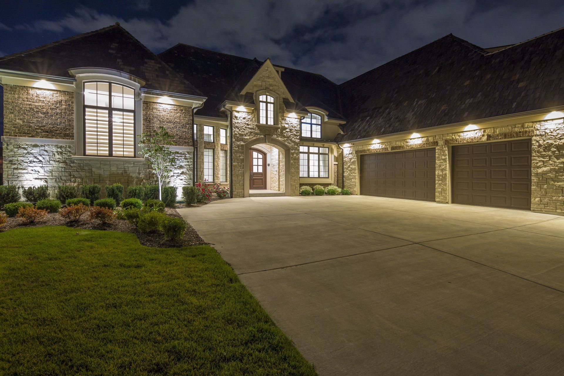 A large house with a lot of garage doors is lit up at night.