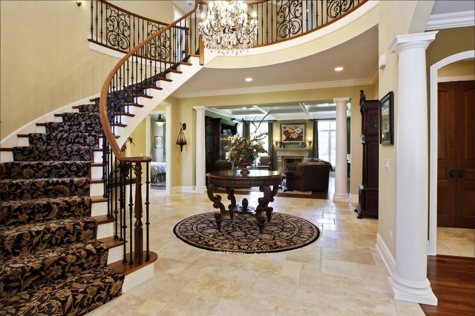 A curved staircase in a large house with a chandelier