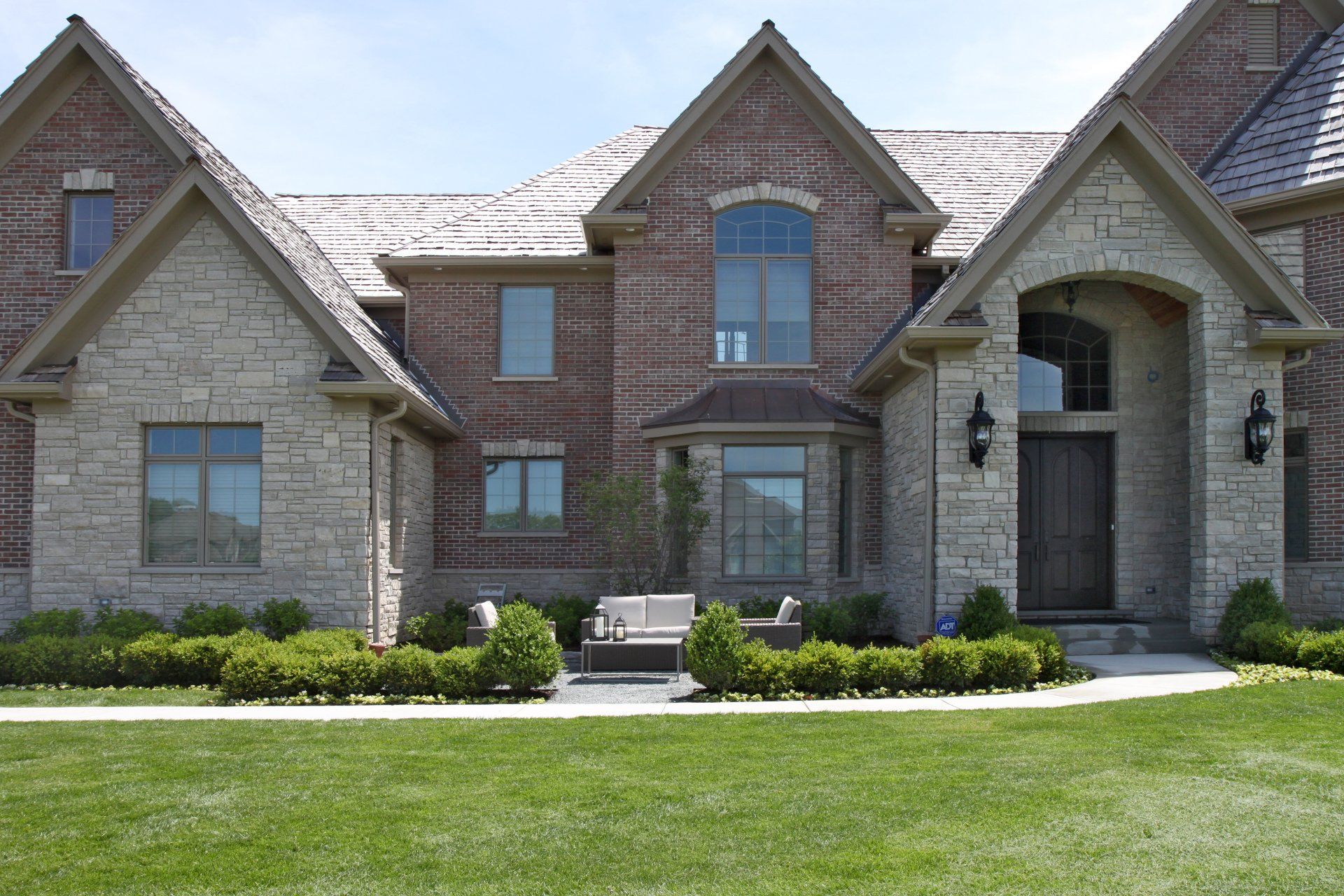 A large brick house with a lush green lawn in front of it