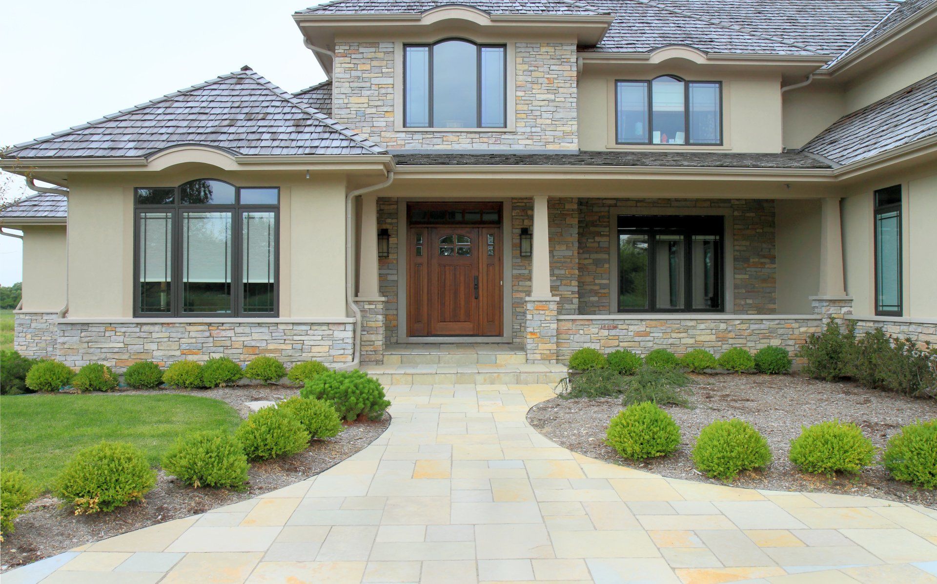 A large house with a wooden door and a stone walkway leading to it.