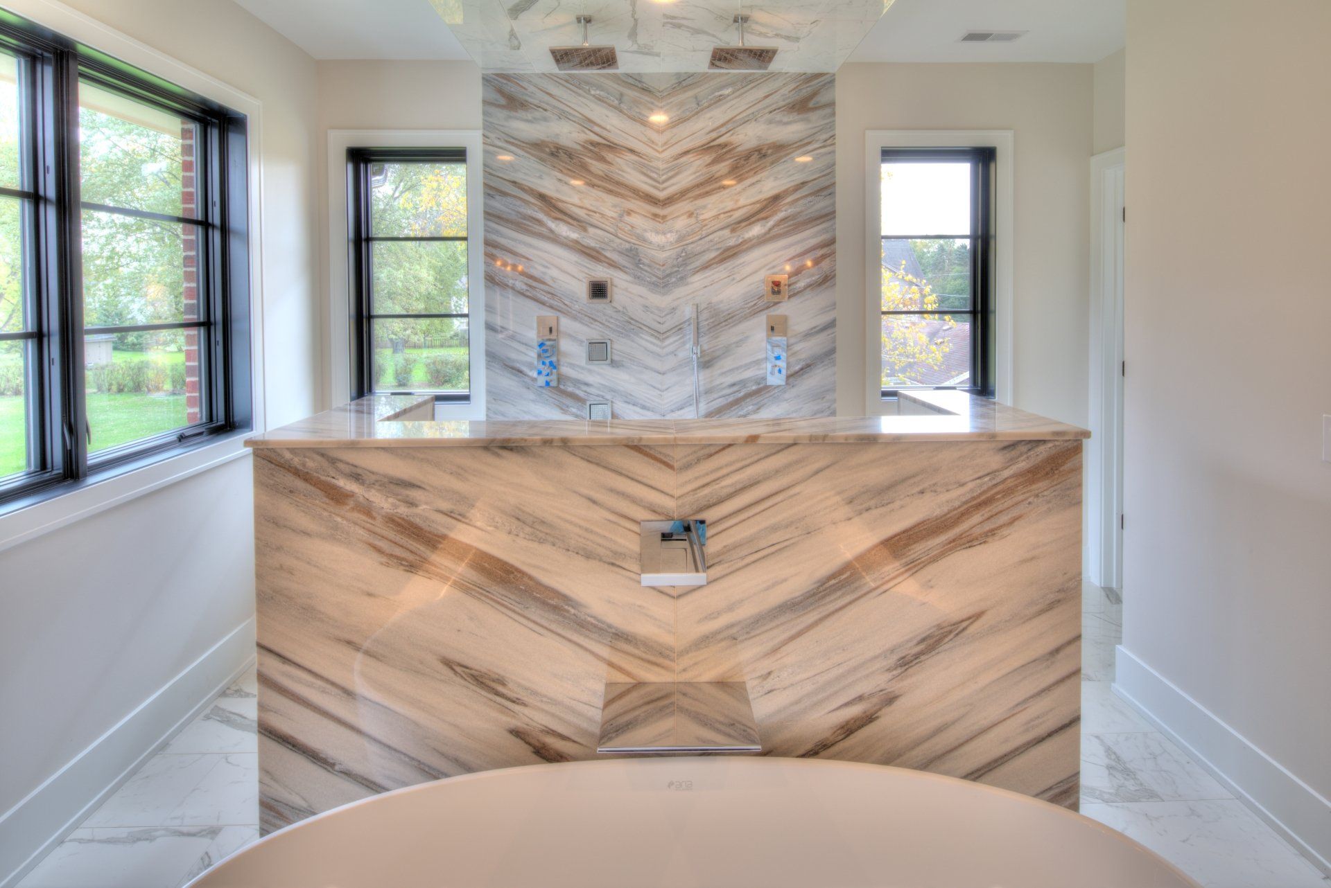 A bathroom with a large tub and a marble wall.