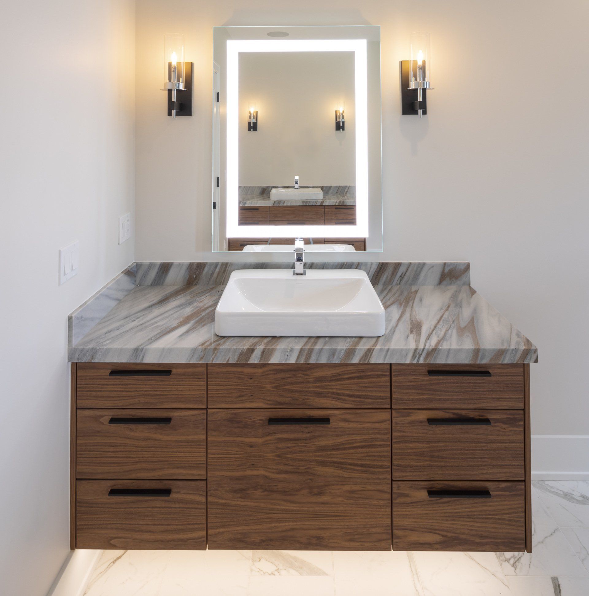 A bathroom with a sink , mirror and drawers
