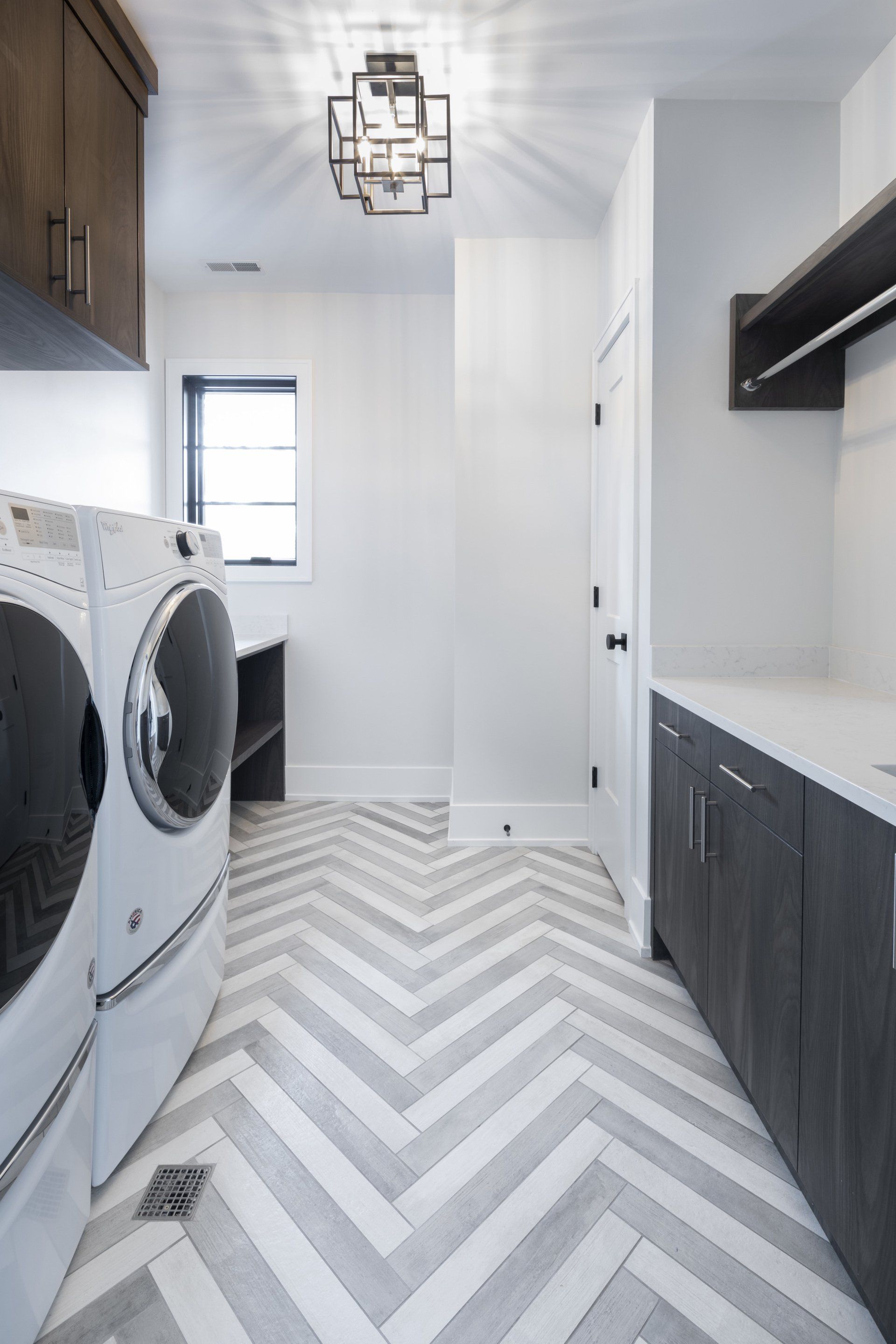 A laundry room with a washer and dryer and a herringbone floor.