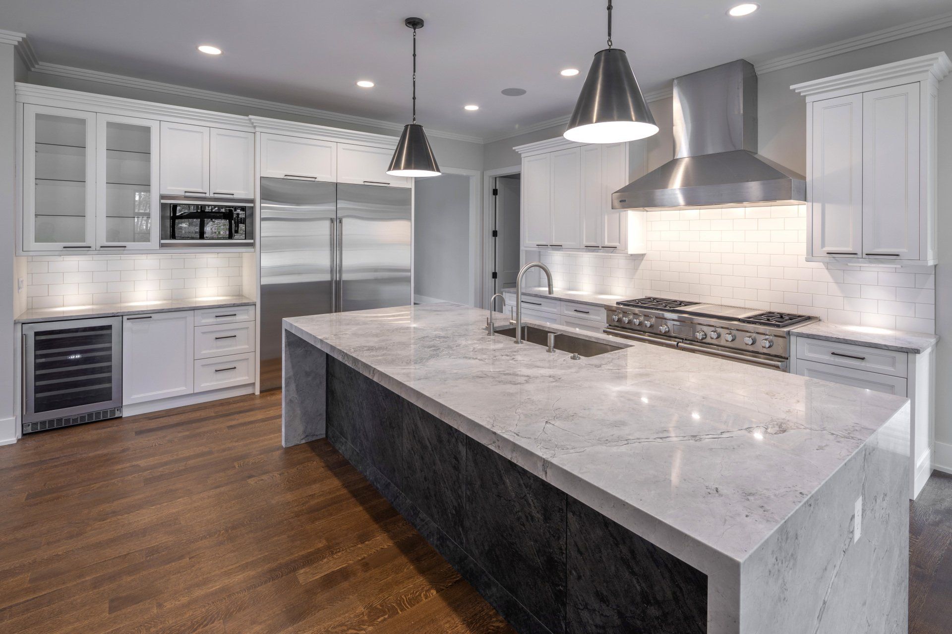 A kitchen with white cabinets , granite counter tops , stainless steel appliances and a large island.