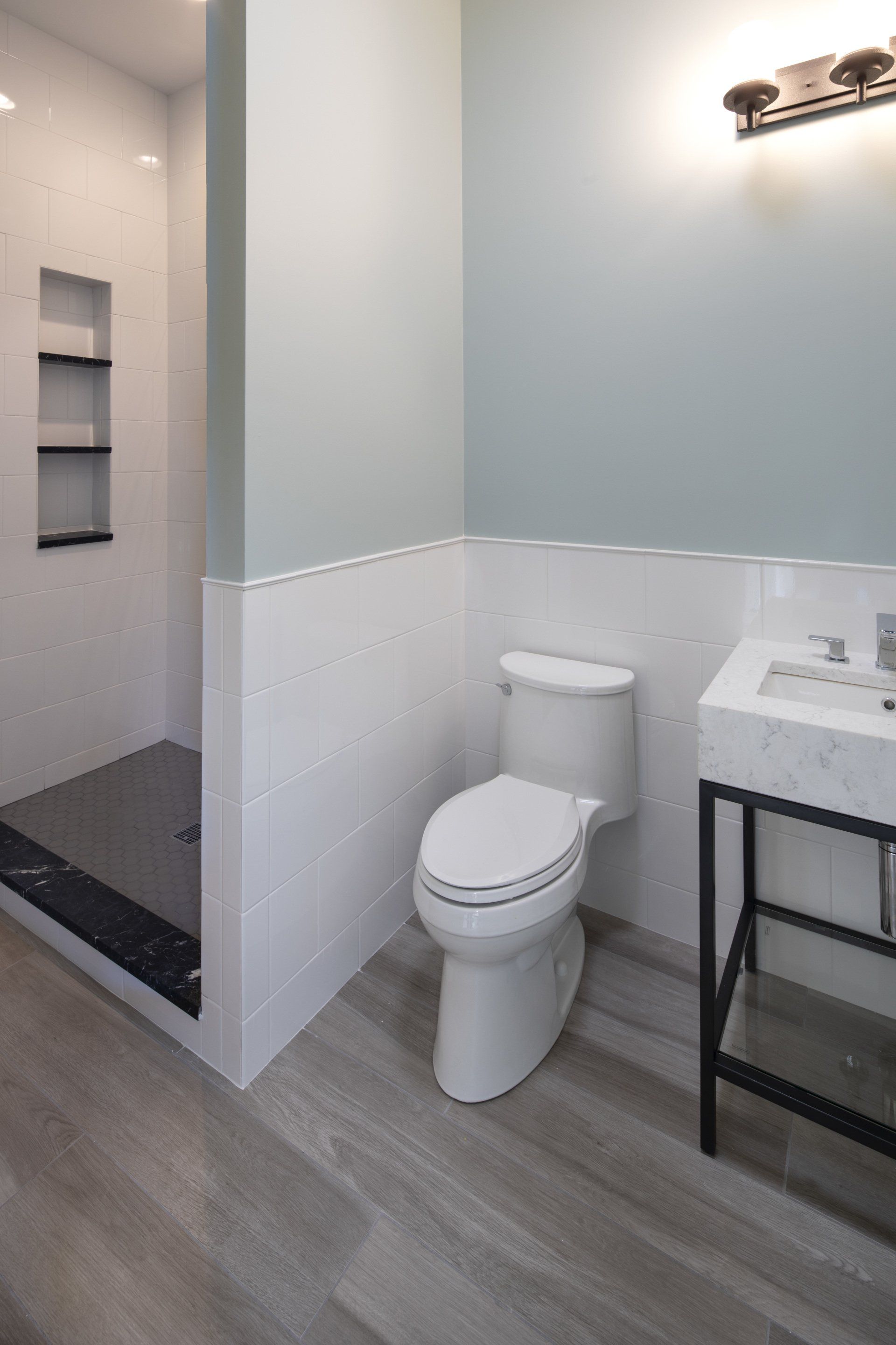 A bathroom with a toilet , sink and shower.