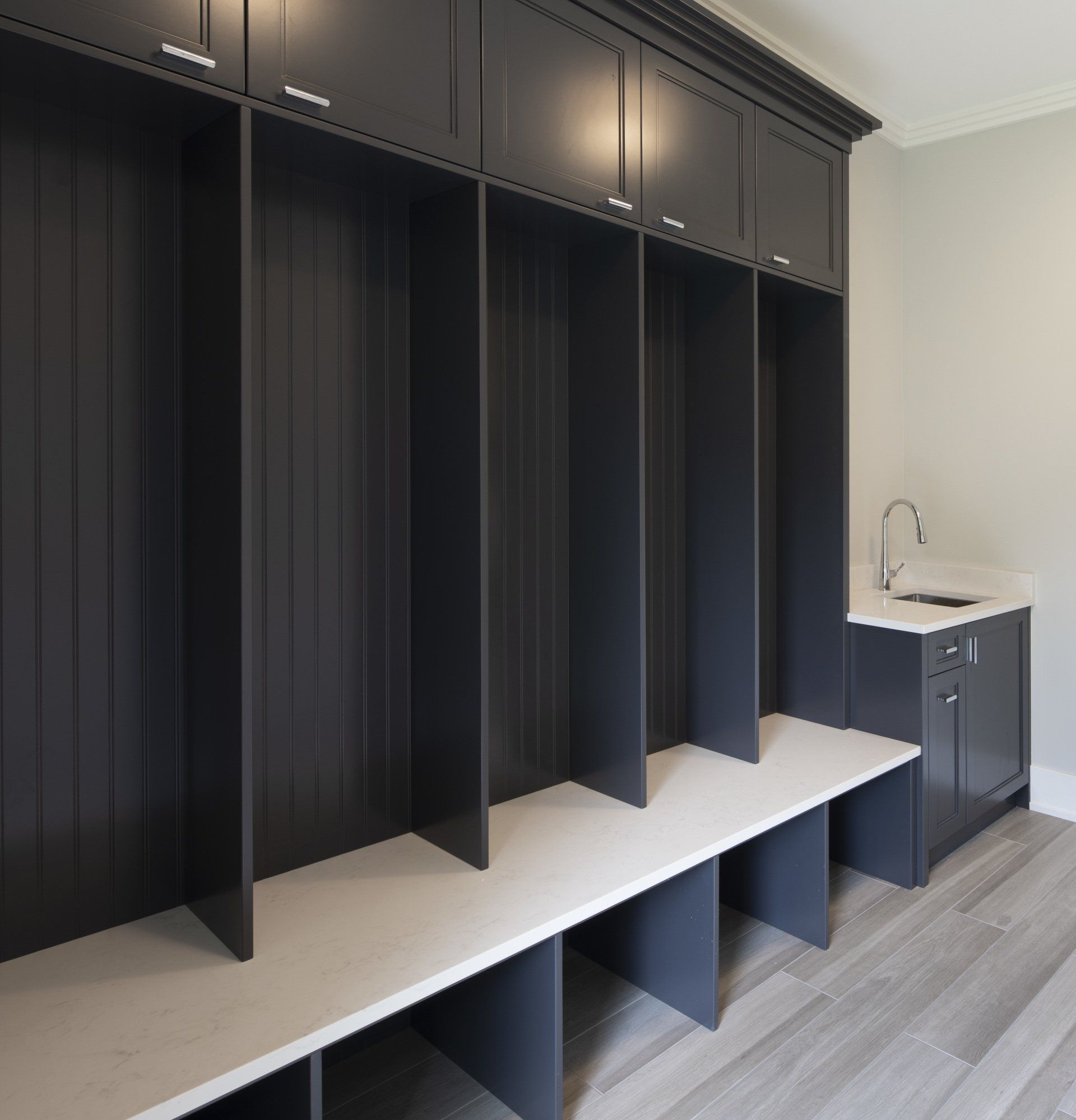 A laundry room with black cabinets and a sink