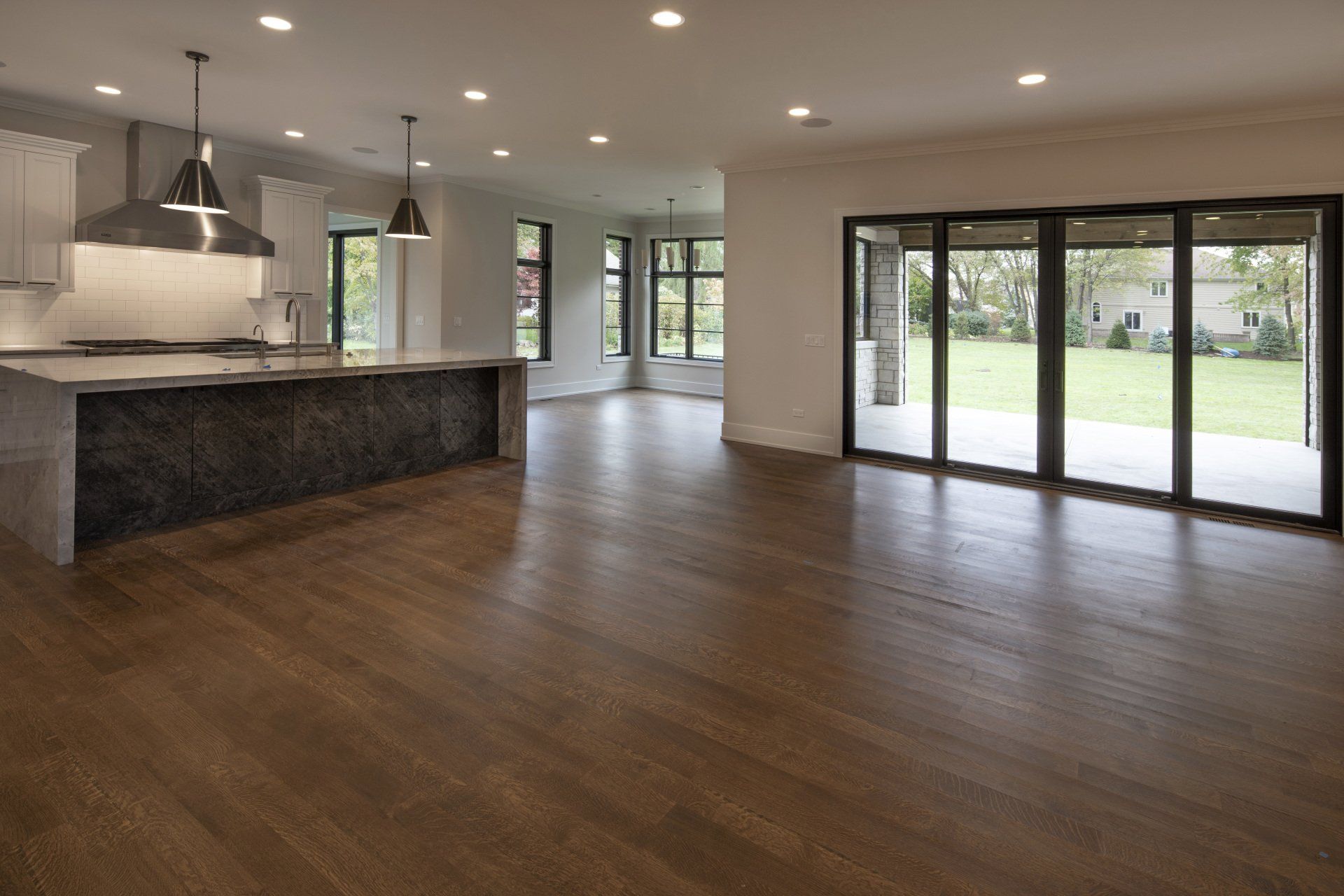 An empty kitchen with hardwood floors and sliding glass doors