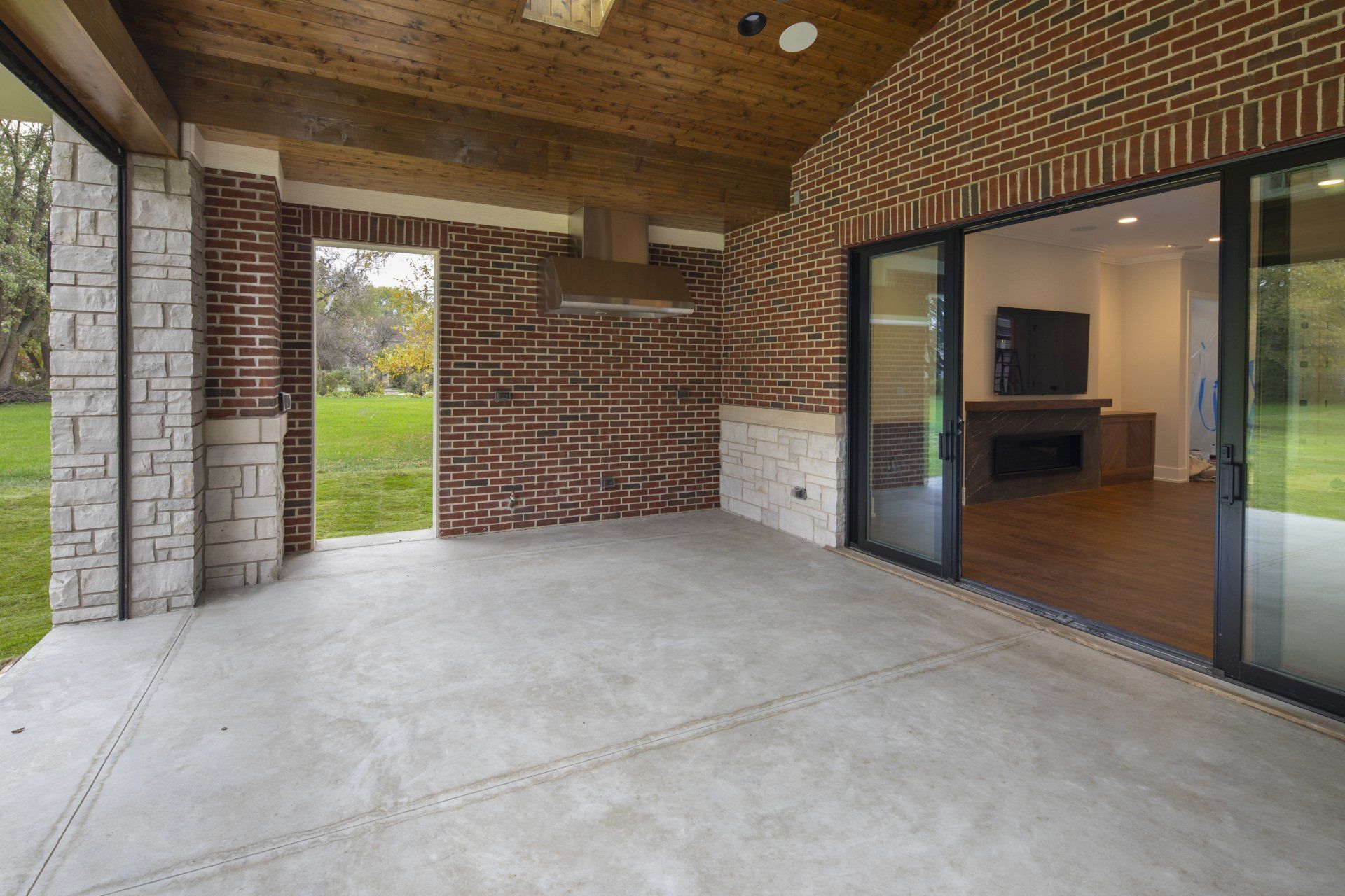 A large patio with sliding glass doors and a brick wall.