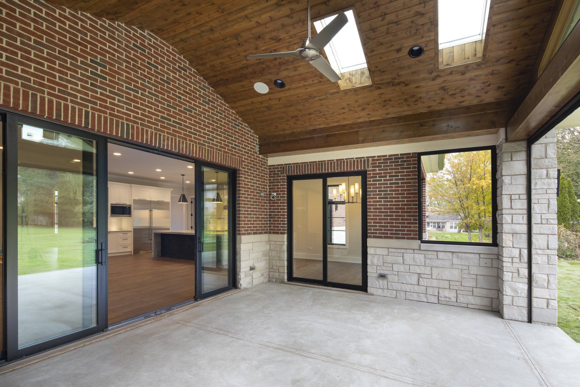 A large patio with sliding glass doors and a ceiling fan.