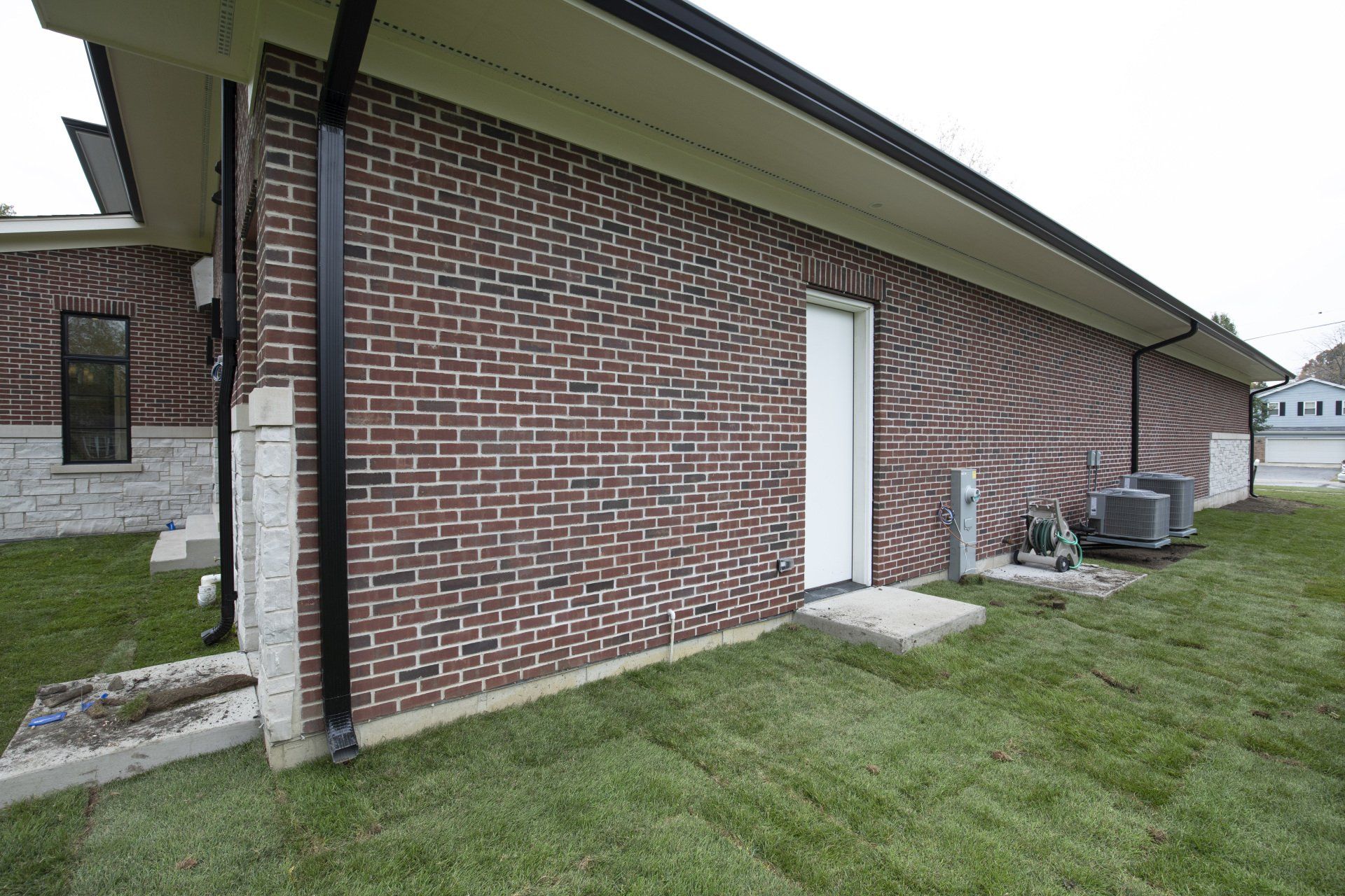 A brick building with a white door and a black gutter