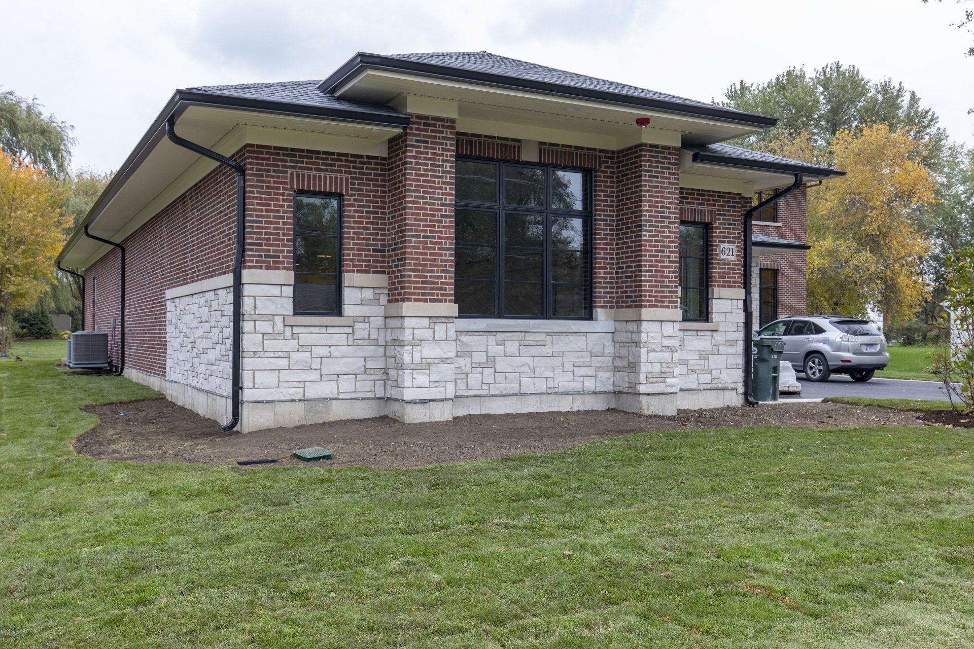 A small brick and stone house with a car parked in front of it.