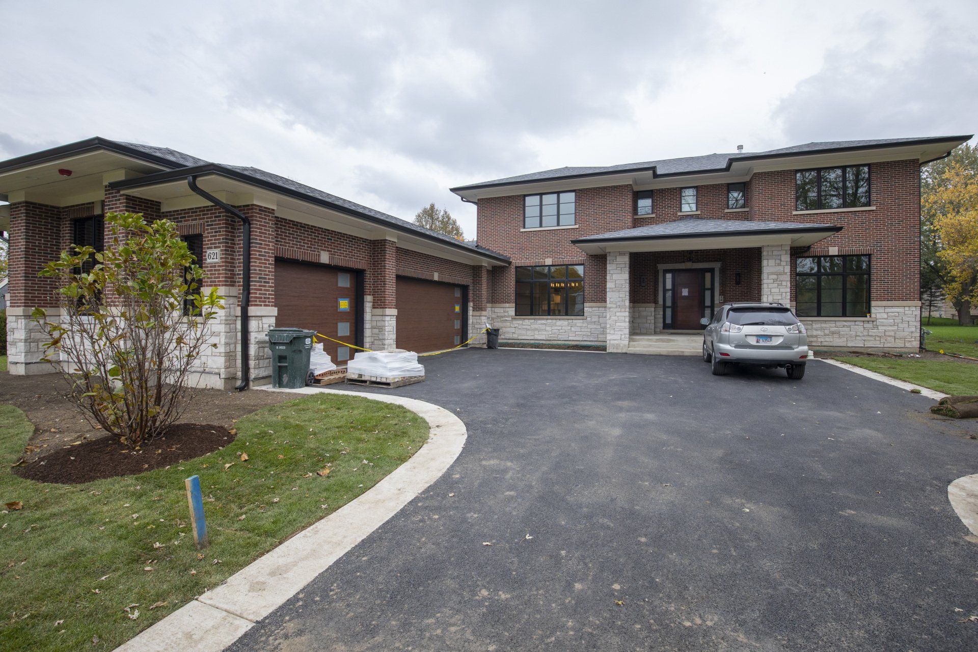 A car is parked in front of a large brick house.