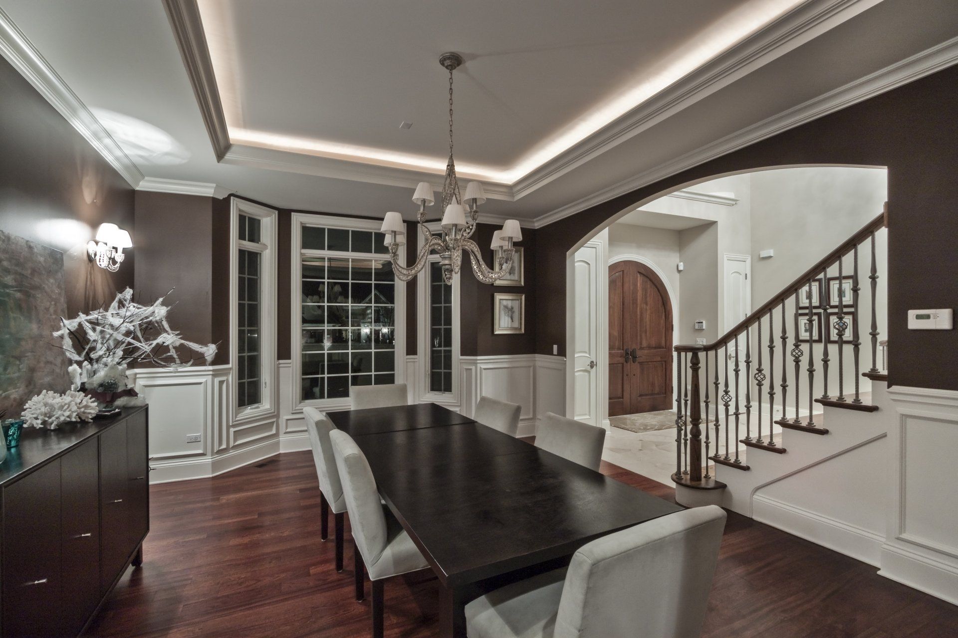 A dining room with a long table and chairs and a staircase.