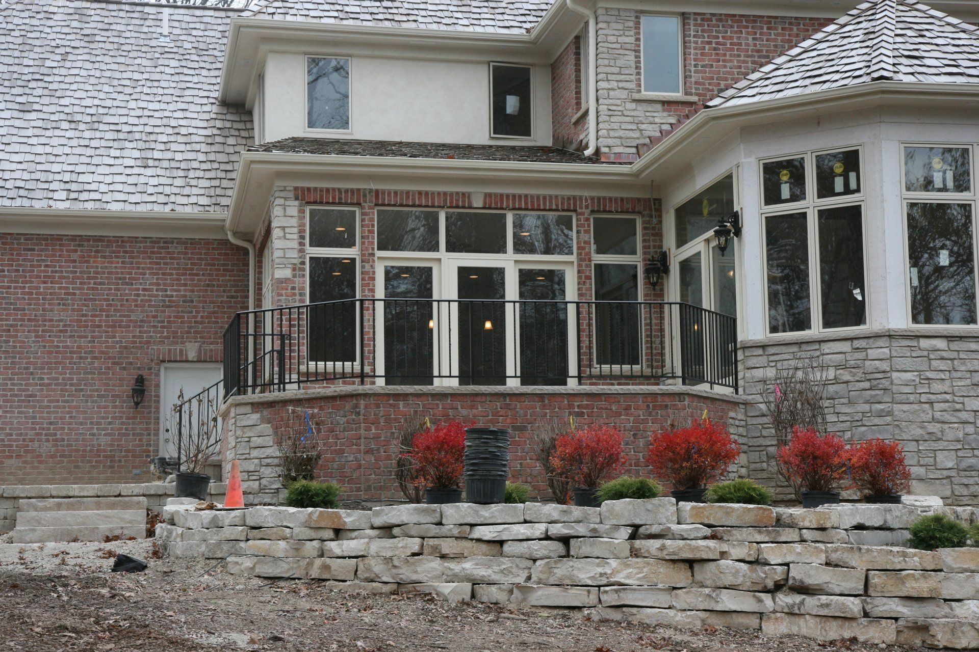 A large brick house with a stone wall in front of it