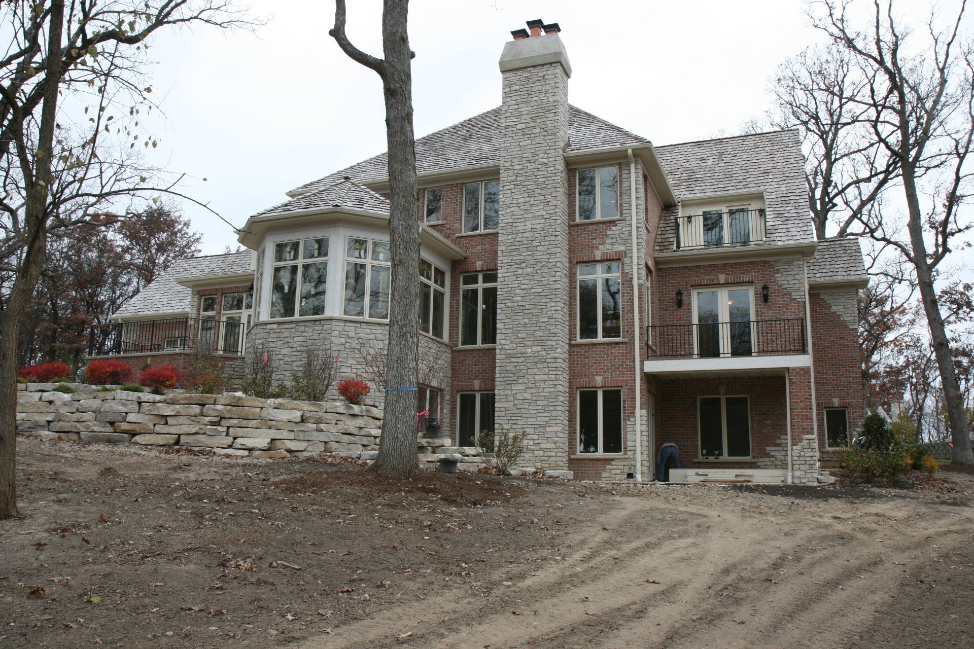 A large brick house sits on top of a dirt hill