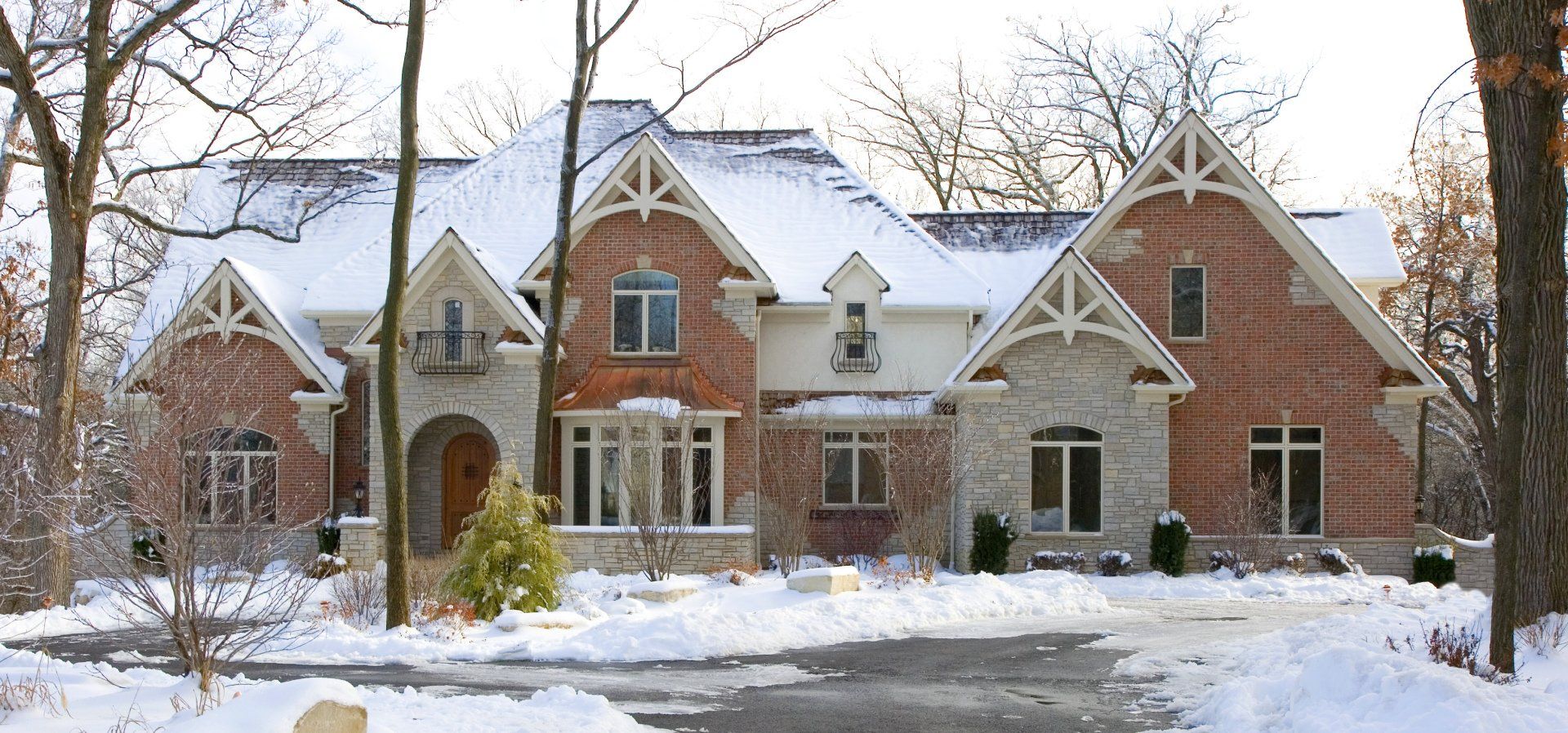 A large brick house with a snowy driveway in front of it