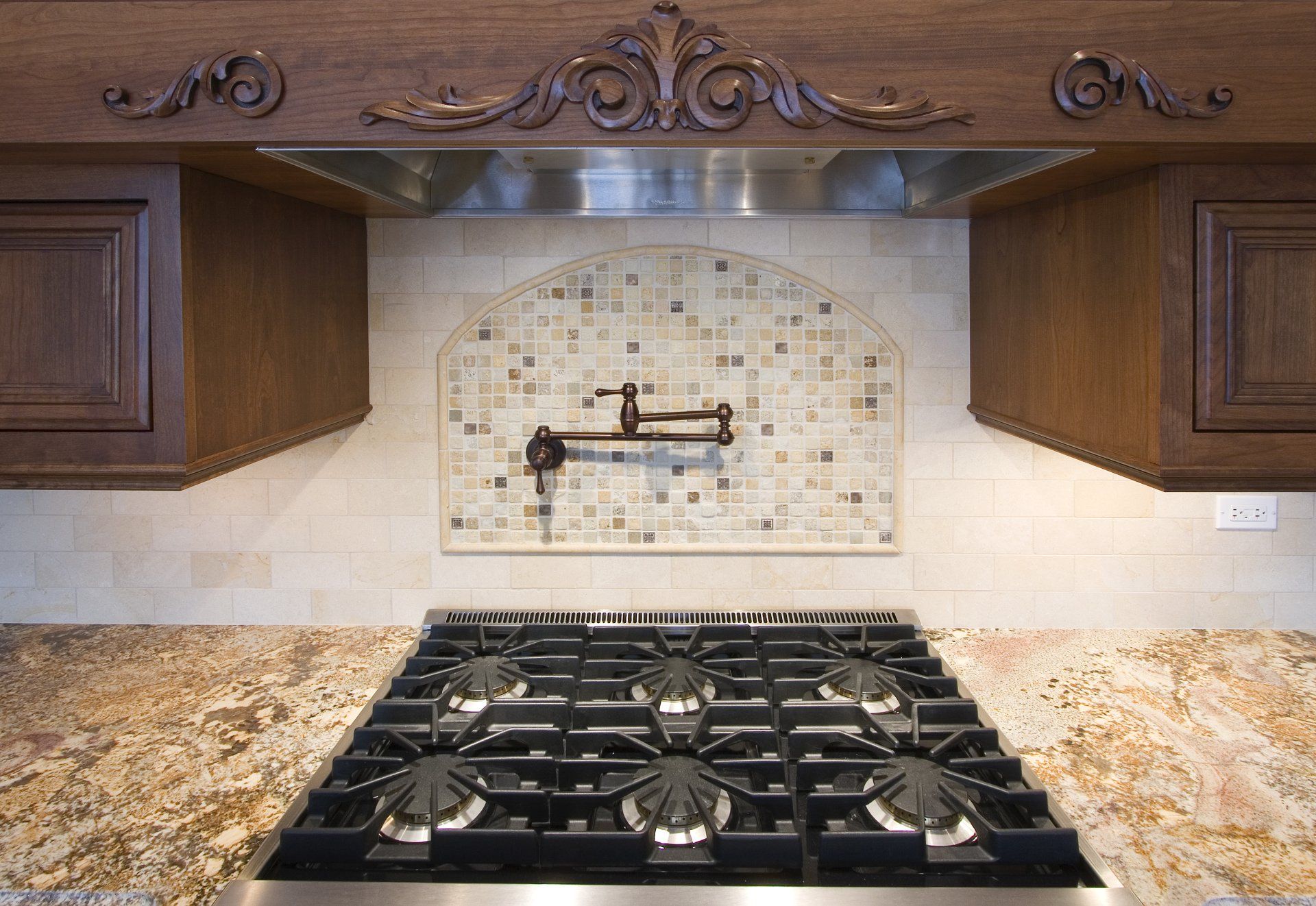 A kitchen with a stove top oven and a stainless steel hood
