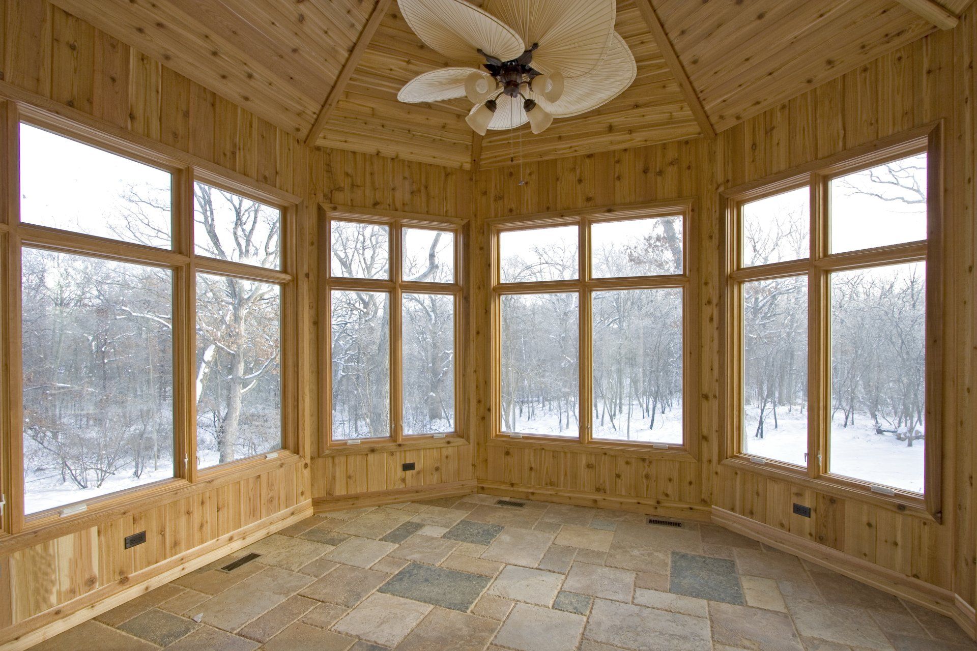 A room with a lot of windows and a ceiling fan