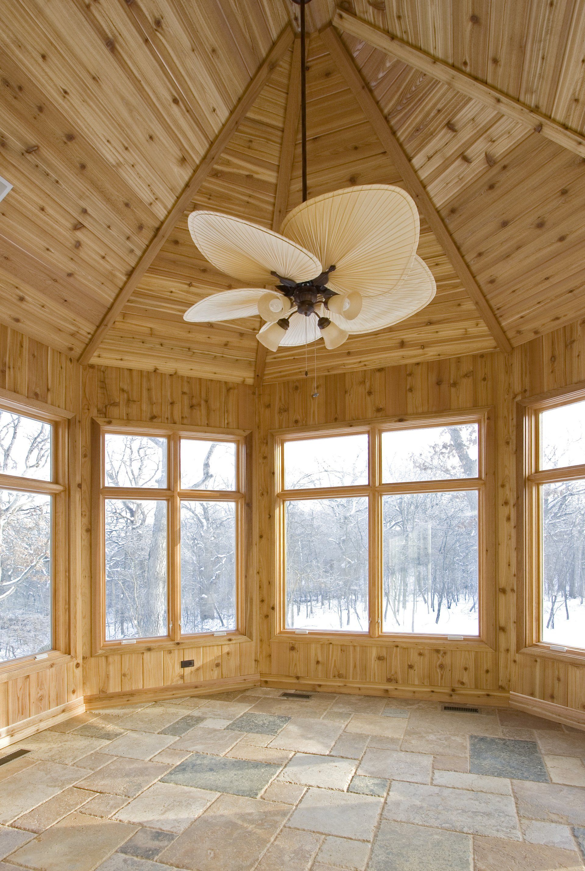 A room with a ceiling fan and lots of windows