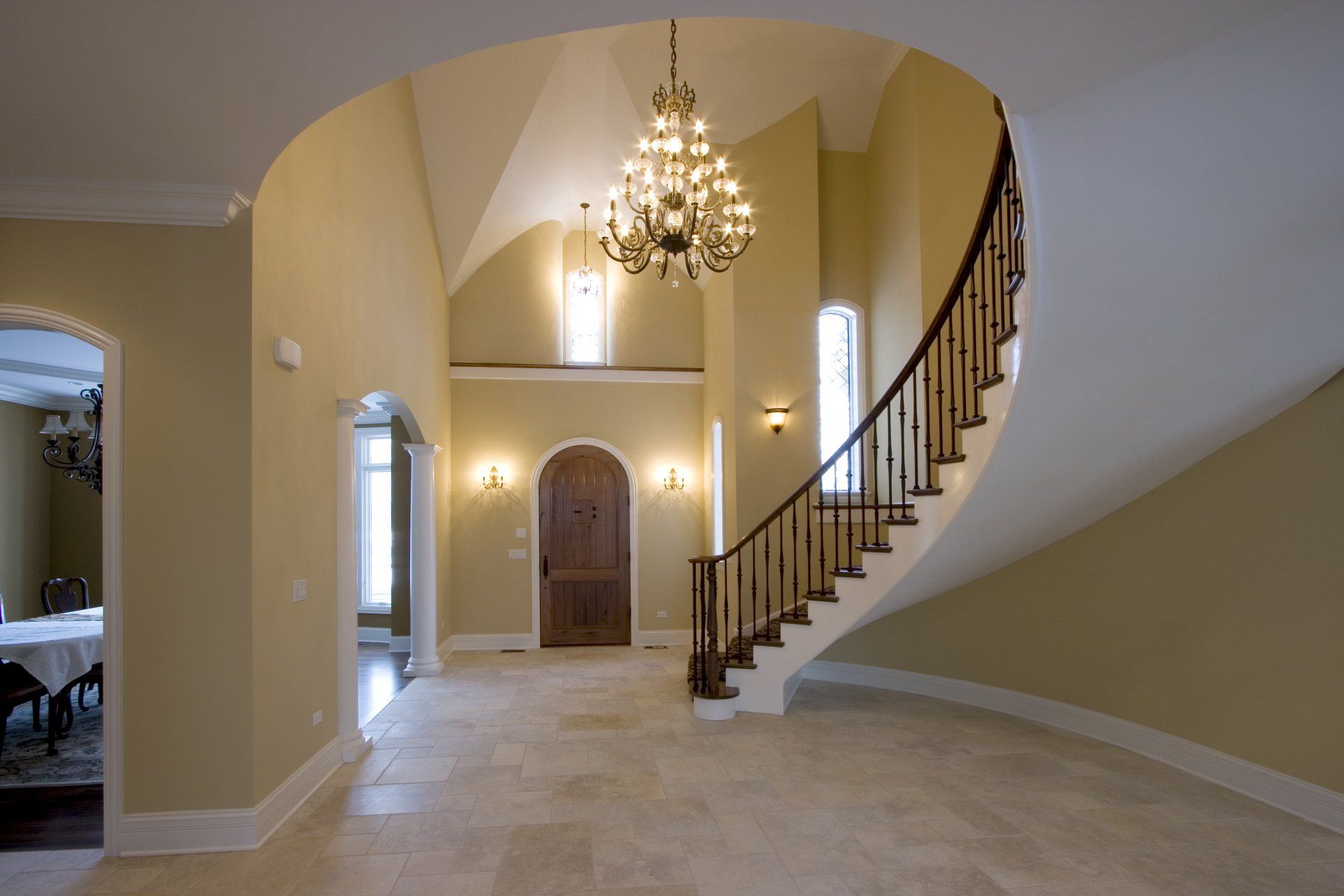 A curved staircase with a chandelier hanging from the ceiling