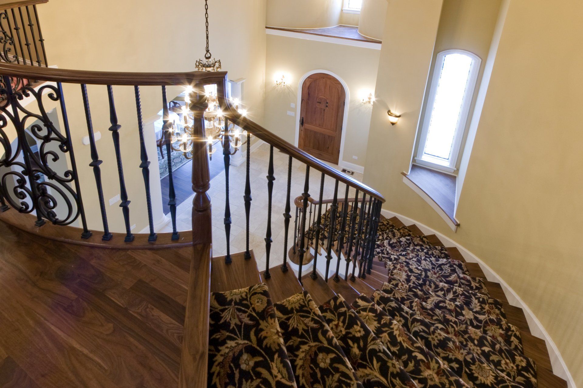 A curved staircase with a wrought iron railing and a rug