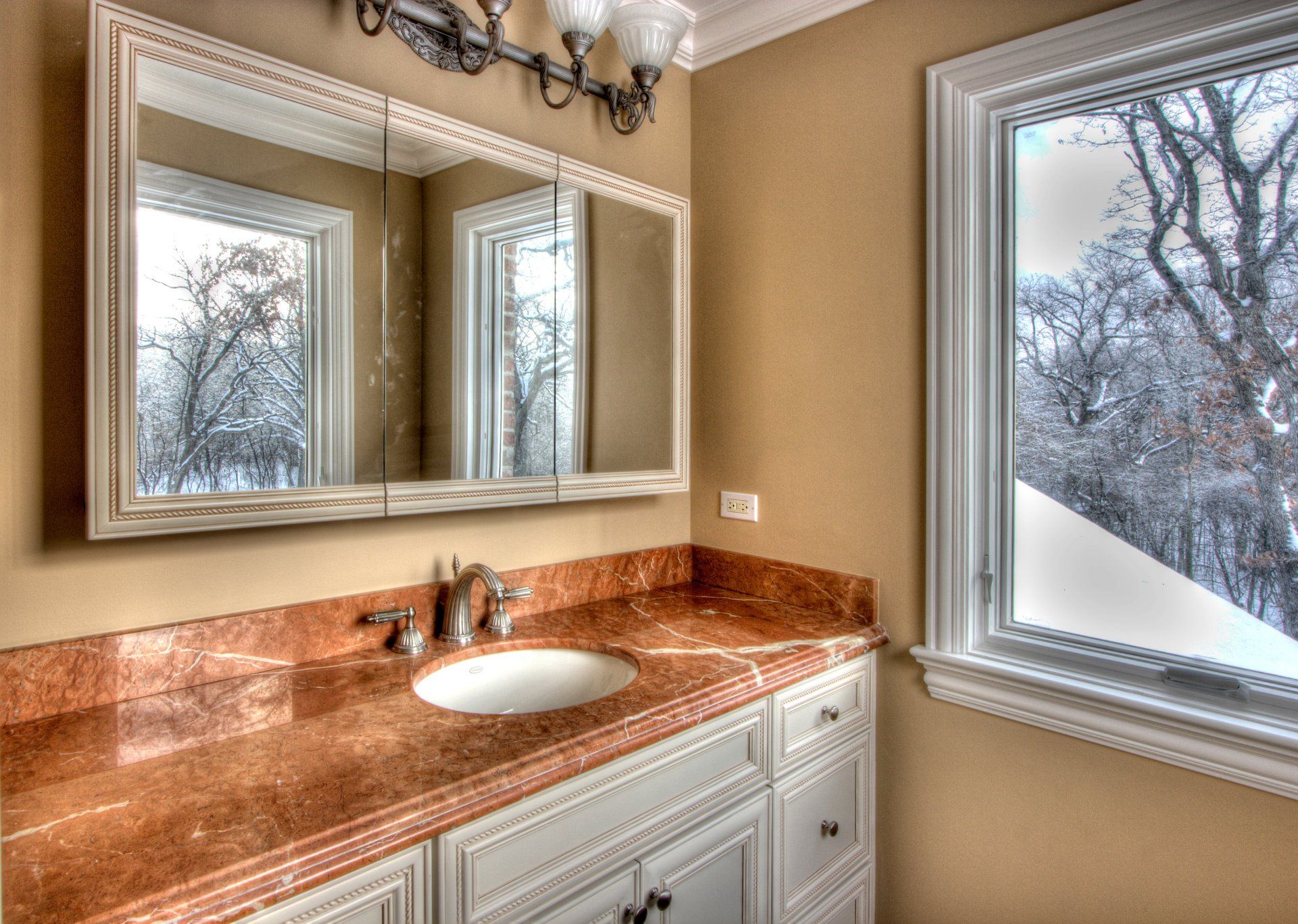 A bathroom with a sink , mirror and window.