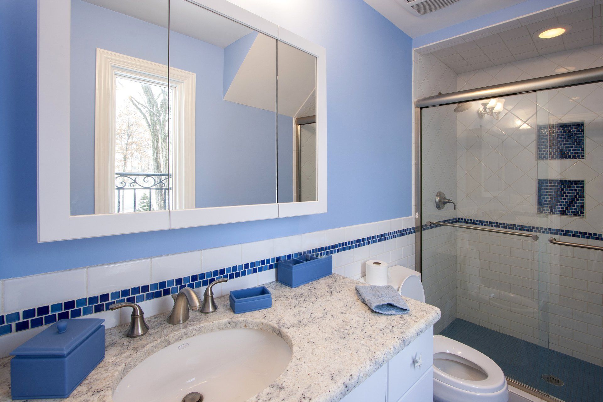 A bathroom with blue walls a sink and a toilet