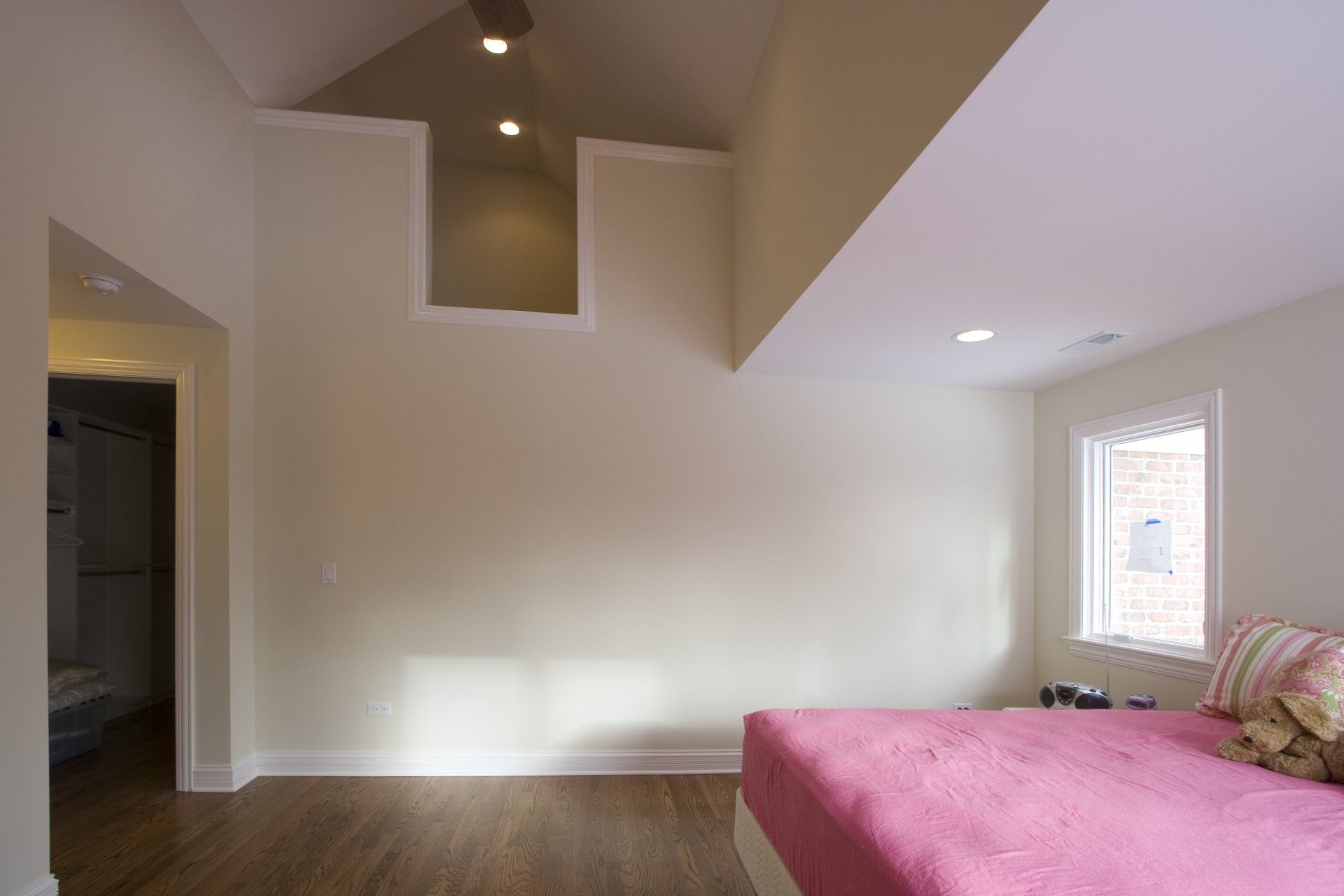A bedroom with a pink bed and a window.