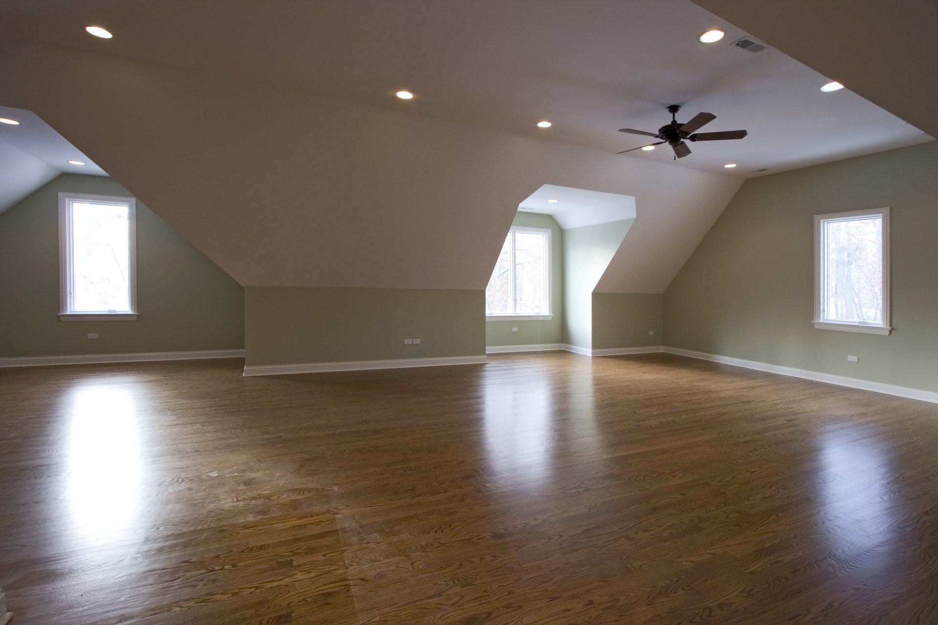 An empty room with hardwood floors and a ceiling fan