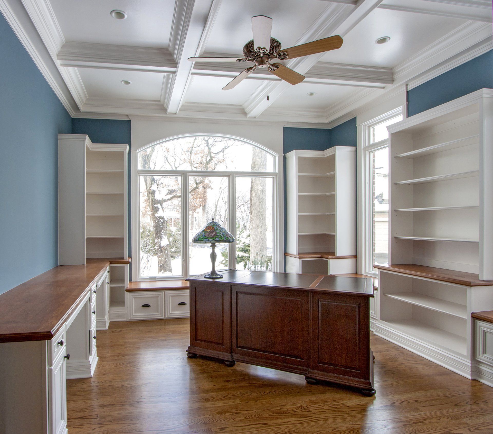 A room with a desk and a ceiling fan