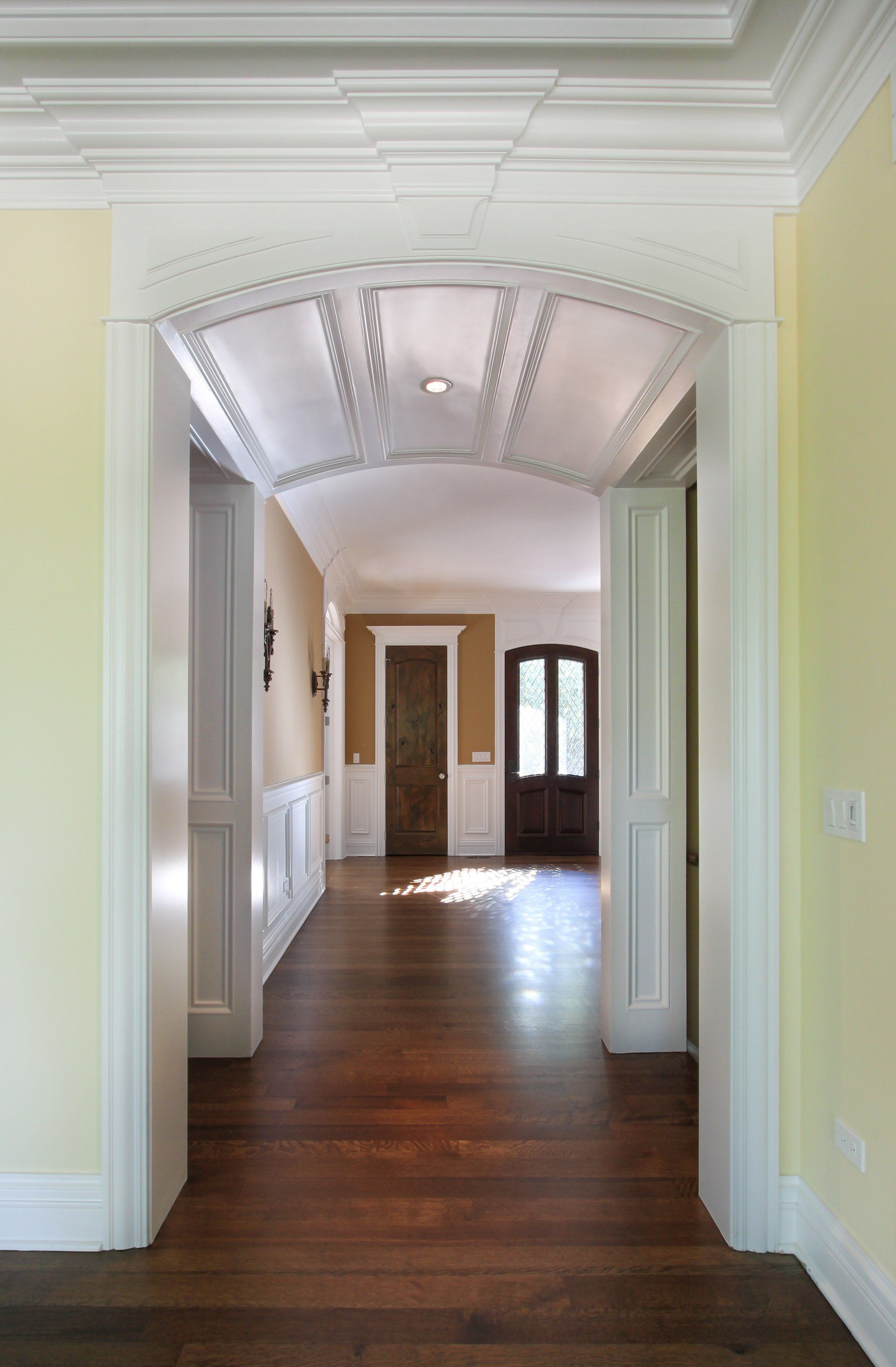 A hallway in a house with yellow walls and wooden floors