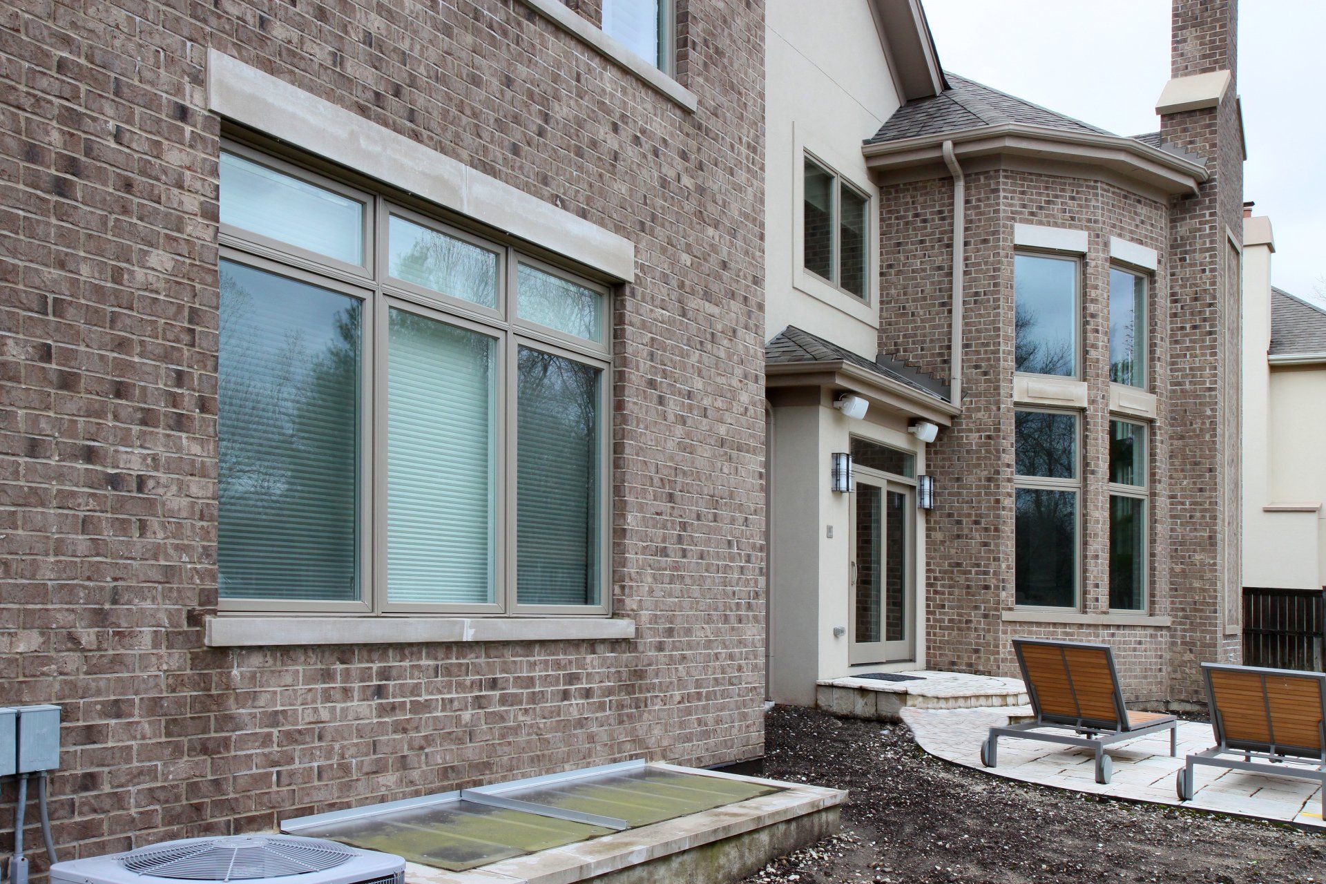 A large brick house with a patio and chairs in front of it