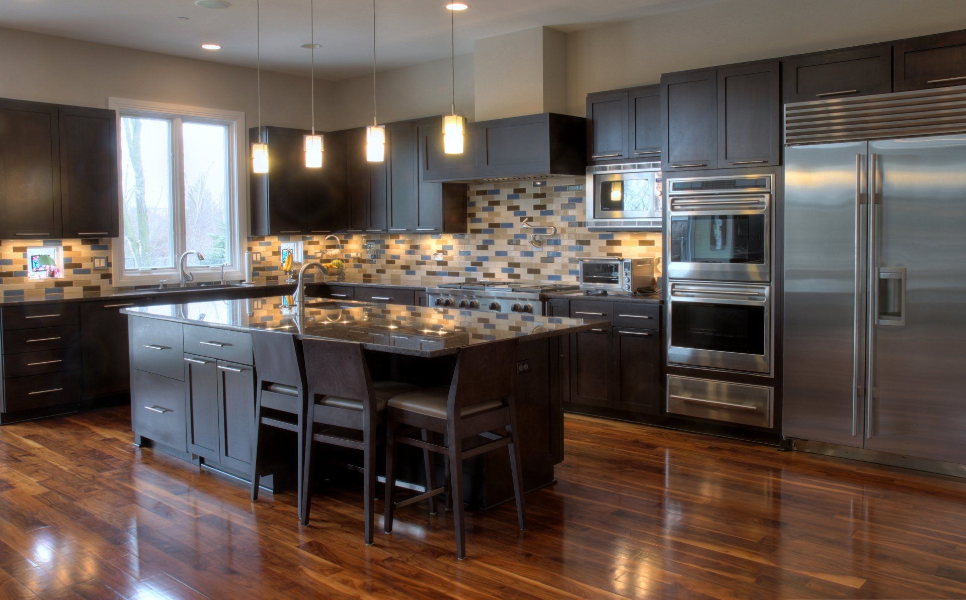 A large kitchen with stainless steel appliances and wooden floors.