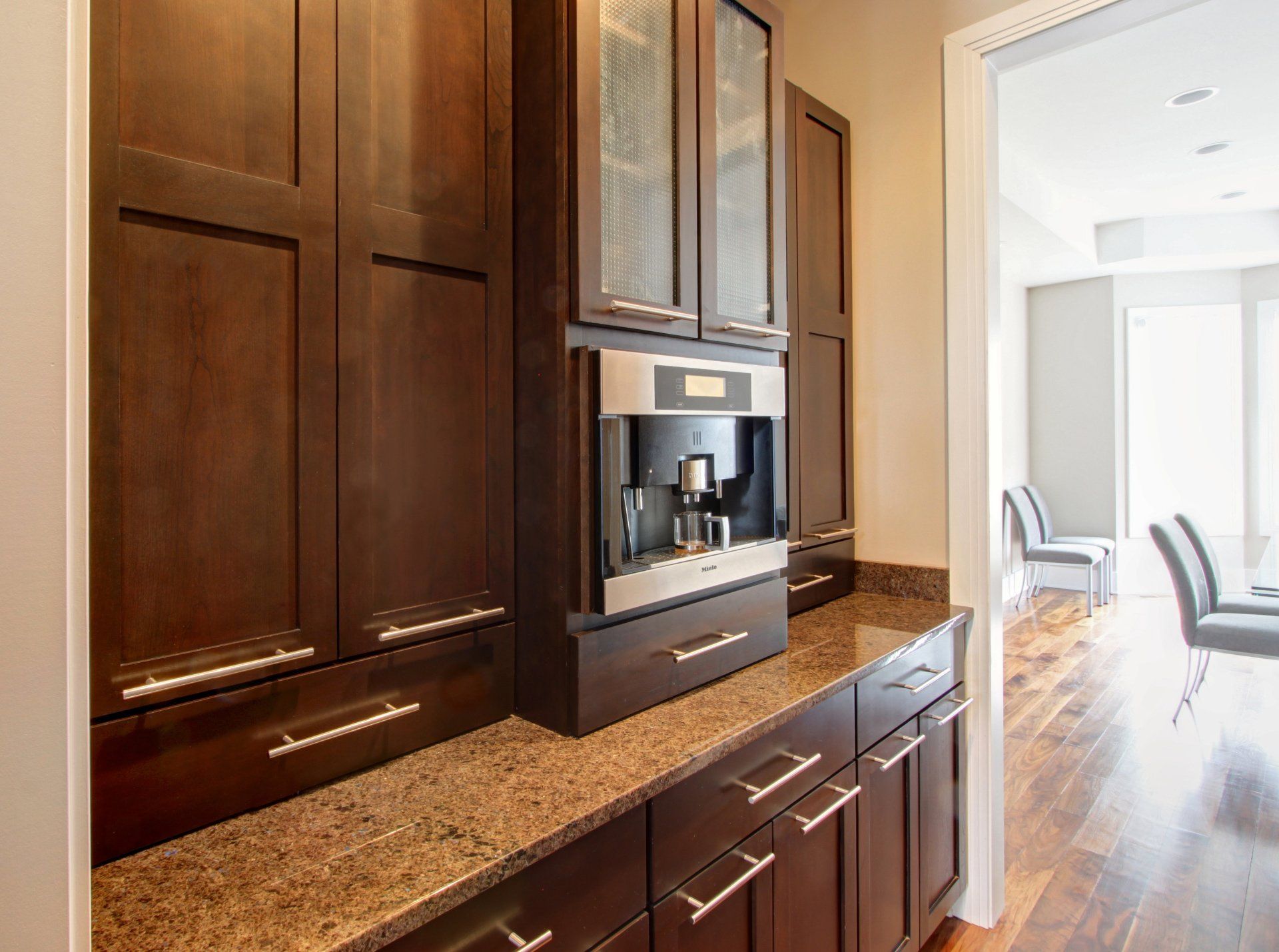 A kitchen with wooden cabinets , granite counter tops , and a coffee maker.