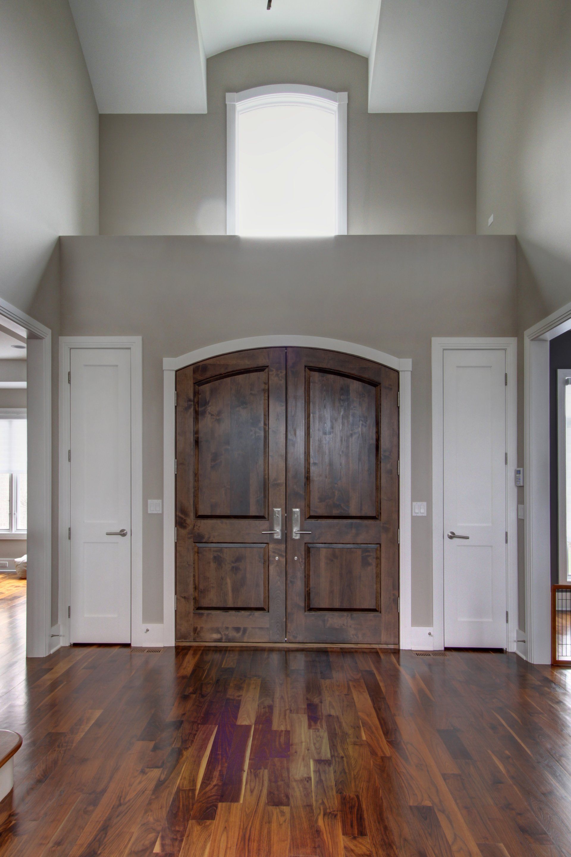 A large hallway with hardwood floors and a wooden door.