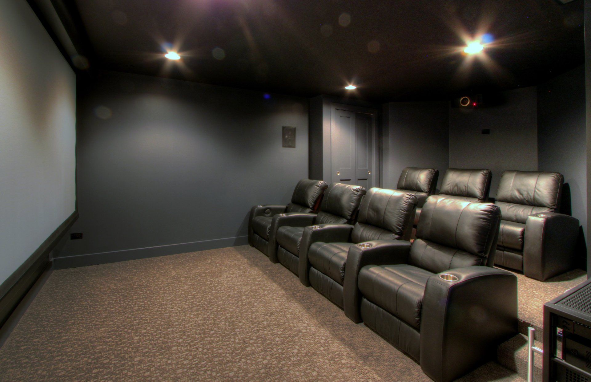 A home theater with black leather seats and a large screen.